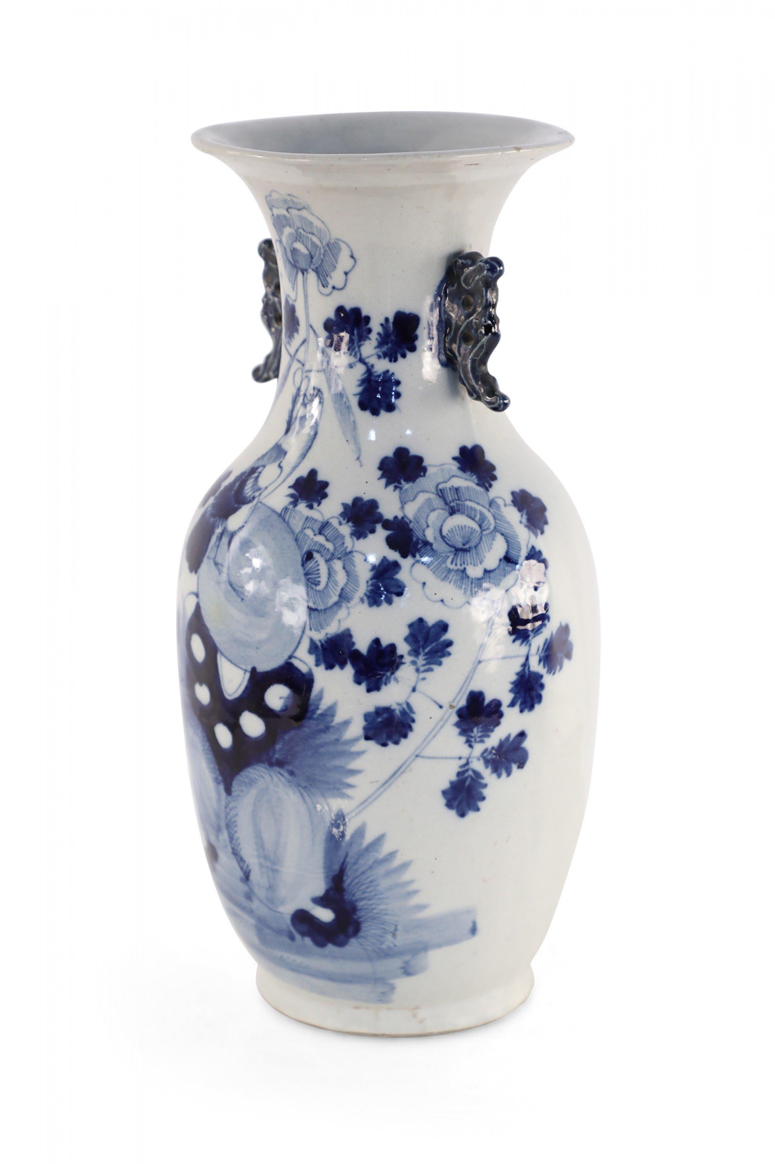 Antique Chinese (Late 19th Century) white and blue porcelain urn decorated with a lily pad and floral motif, and accented in two navy scrolled handles along the neck.
   