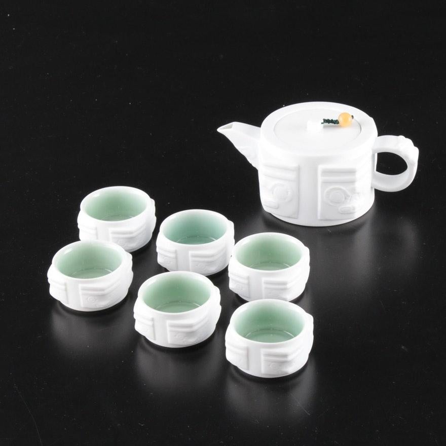 A contemporary Chinese teaware set consisting of six cups and one teapot. Chinoiserie style white ceramic with celadon glazed interior. Dark green teapot lid cord with polished stone bead.

Includes original box/packaging.

Dimensions:
Teapot -