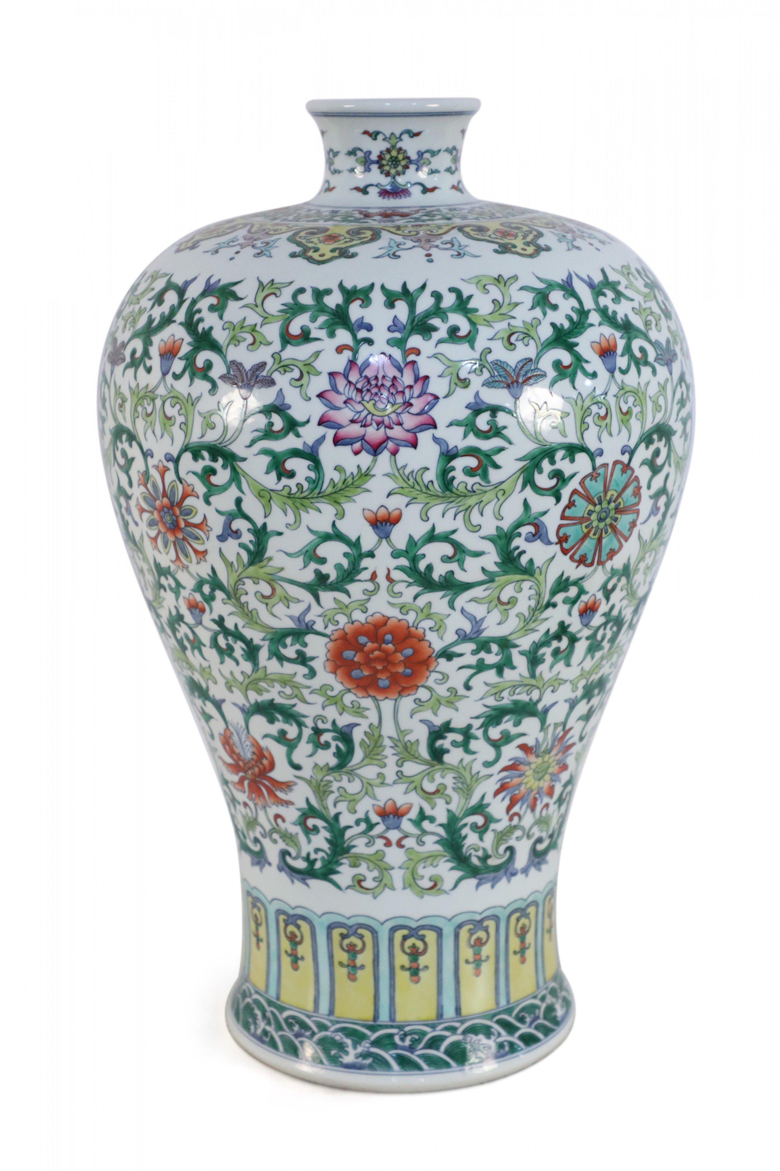 Chinese white porcelain vase with a Meiping form decorated in swirling green vines interspersed with colorful florals.
  