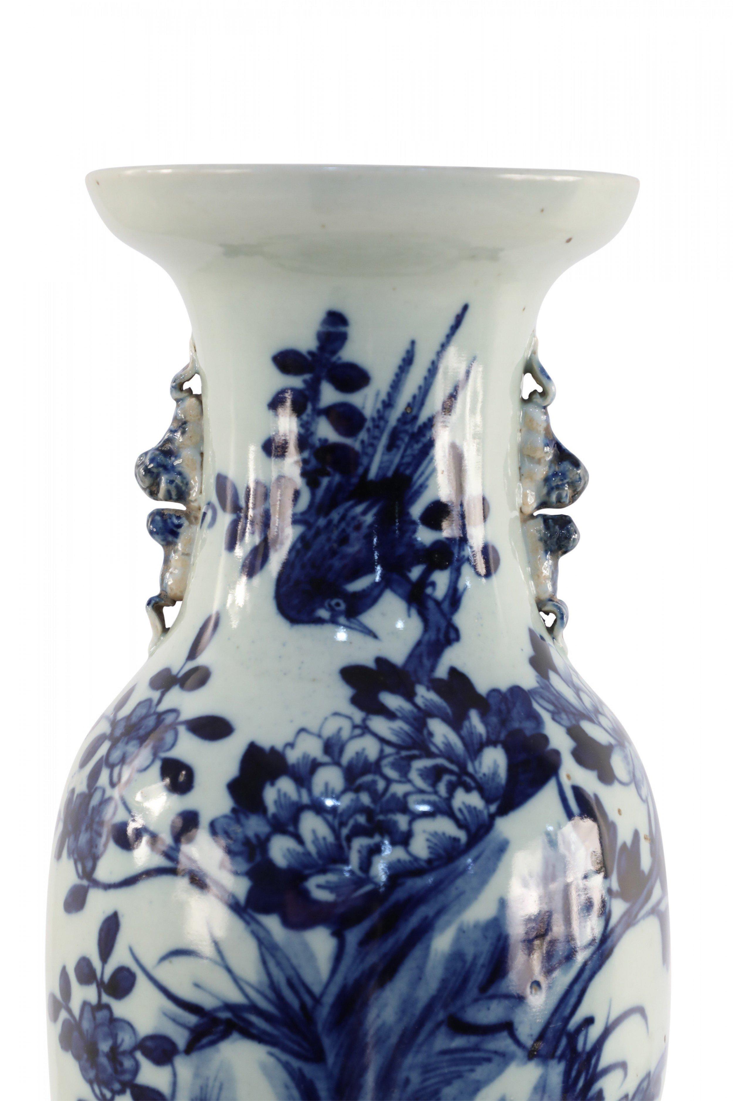 Antique Chinese (Late 19th Century) white, porcelain urn decorated with a blue botanical scene of an oversized peony emerging from a marsh under a bird perched on a flowering branch, and accented with two light blue scrolled handles along the
