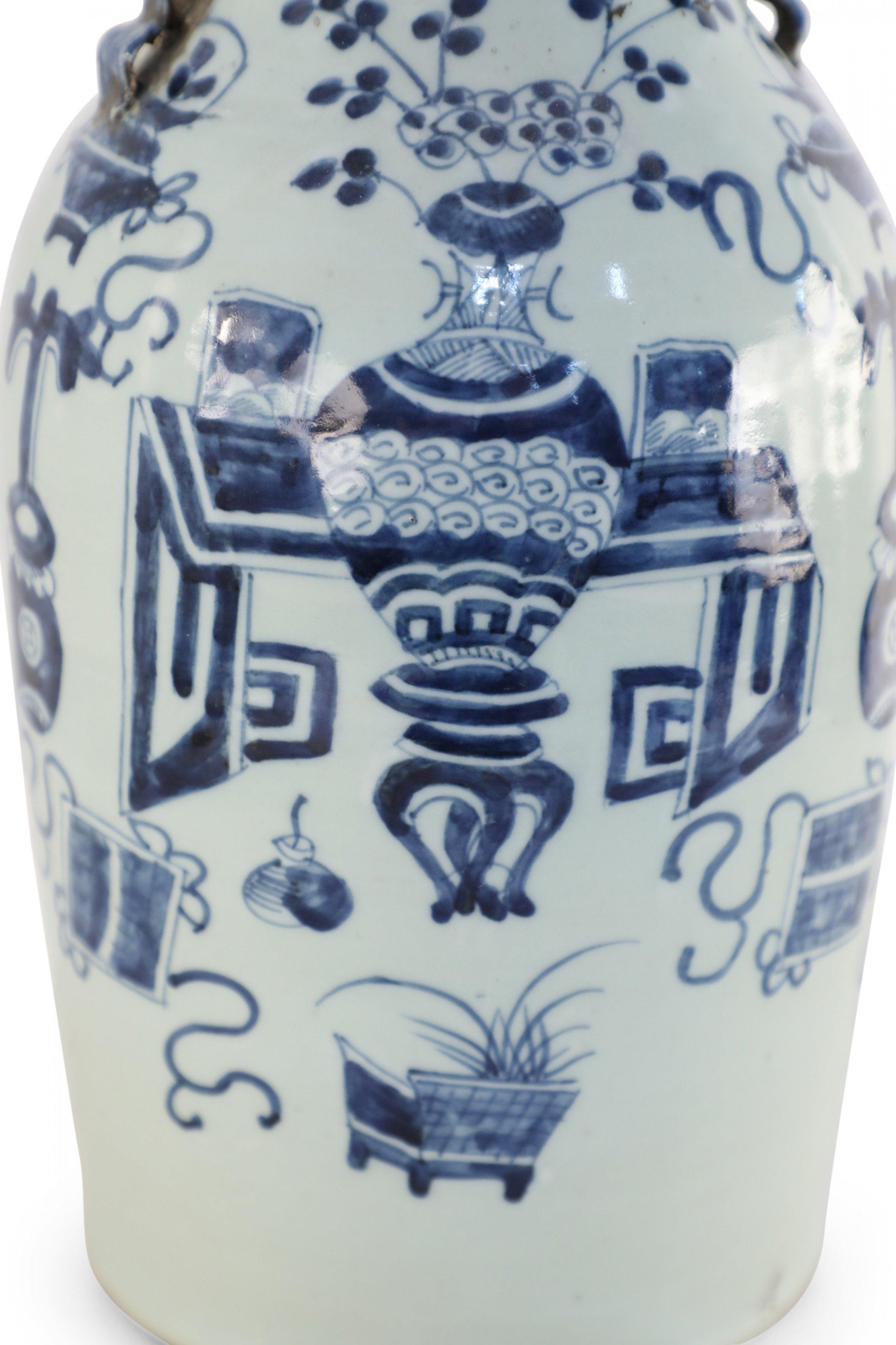 Antique Chinese (Late 19th Century) white porcelain urn painted with a blue pattern featuring urns, furniture, and florals with blue scrolled handles on the neck.
  