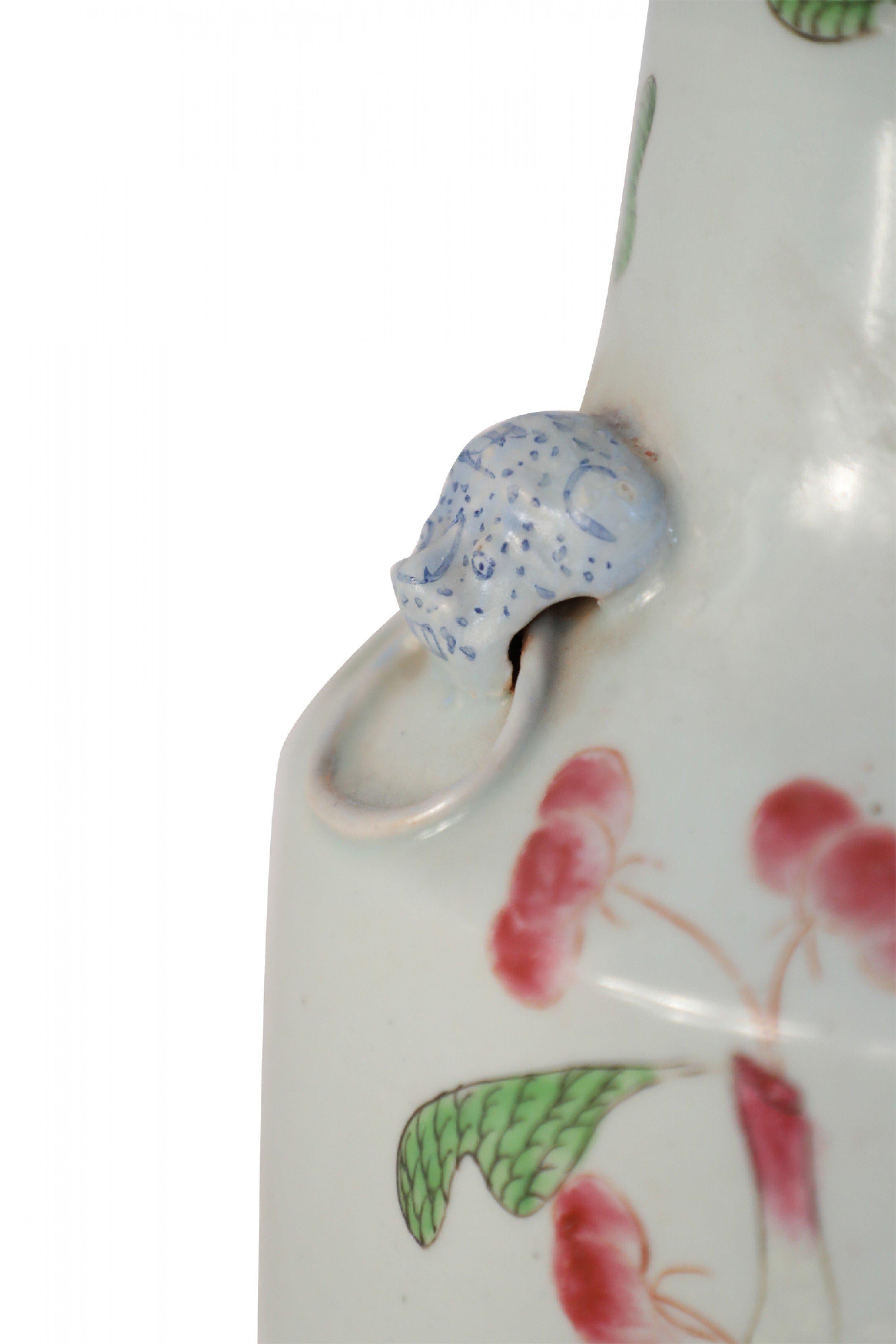 Chinese white porcelain urn decorated with dark pink cherry blossom branches growing up its form, and accented with white foo dog doorknocker ornamentation along the neck.
      