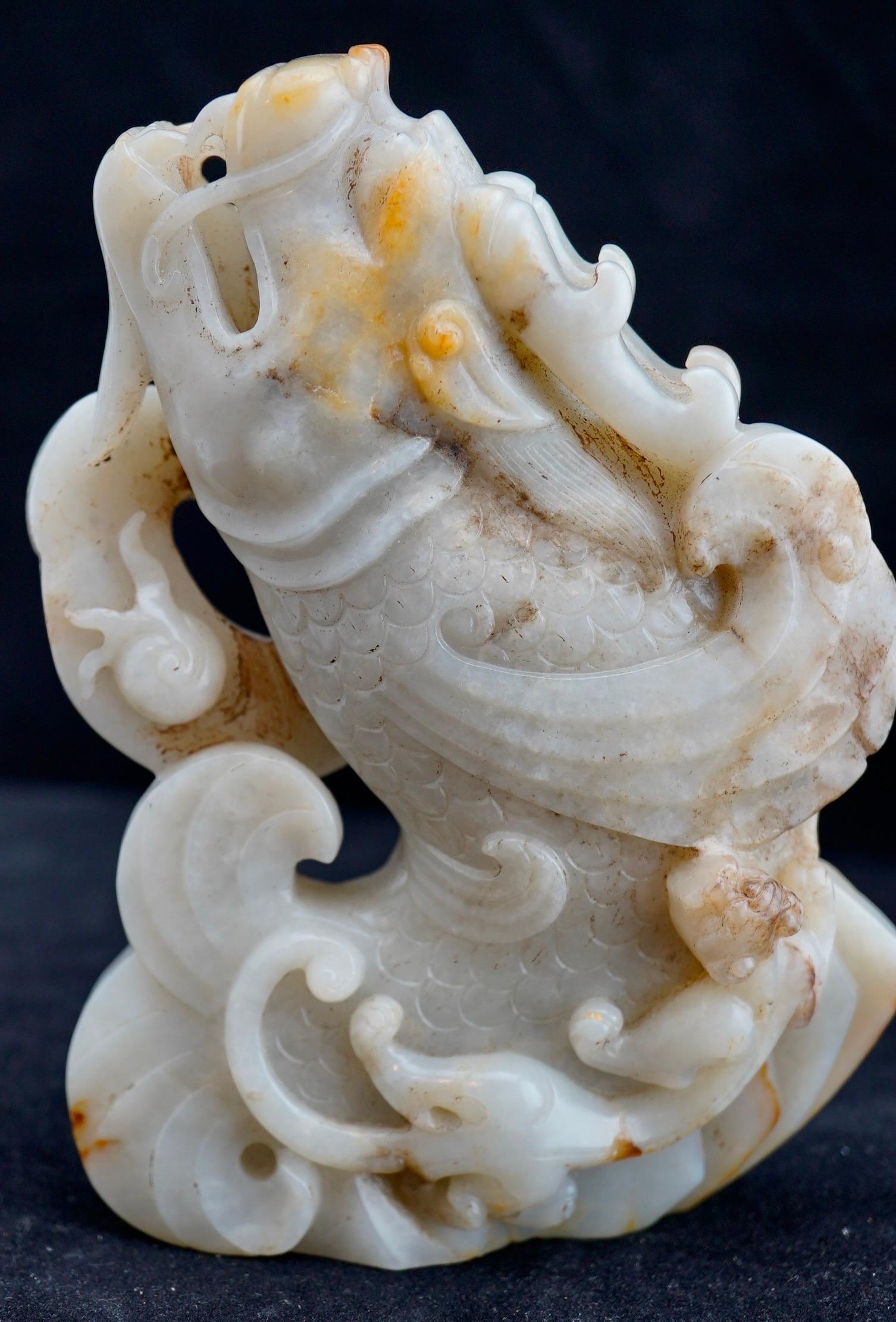 Sculpture en jade blanc et roussâtre représentant une carpe sautant, entourée de vagues,  
chilong et perle flamboyante. Travail du 20e siècle.
