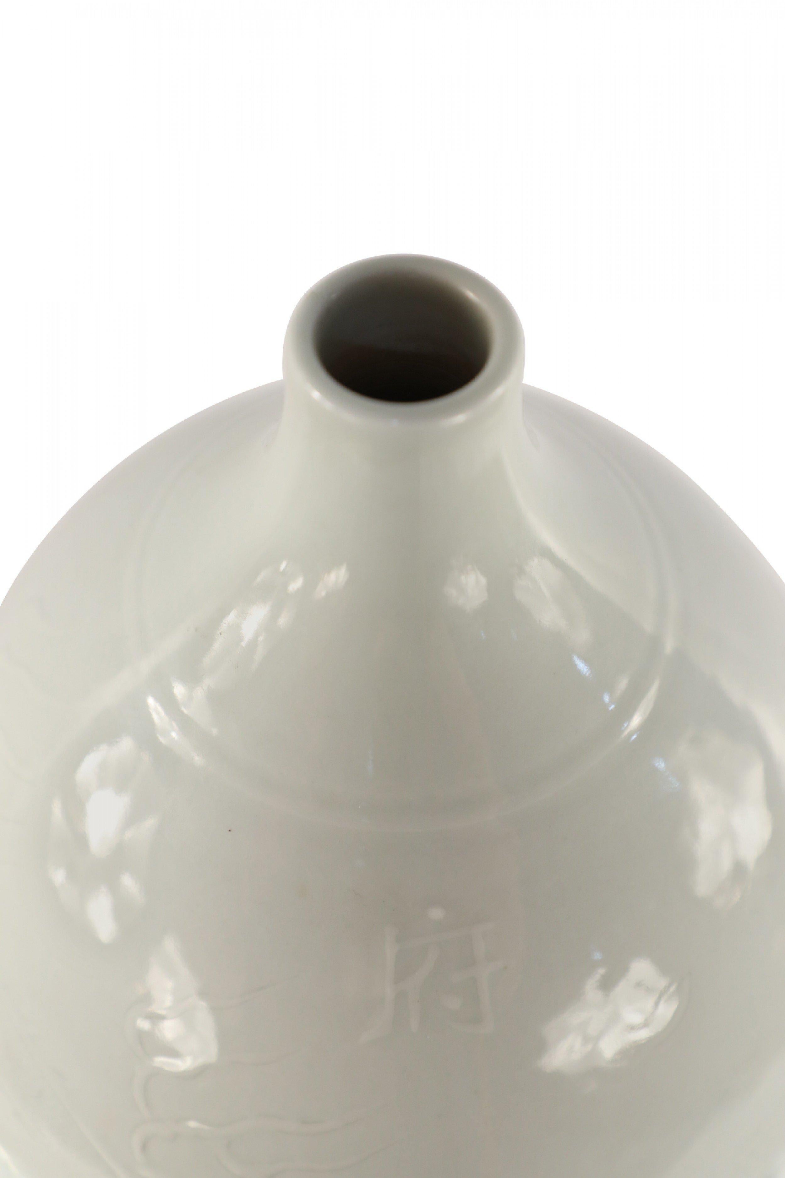 Chinese white, glazed porcelain double gourd bottle thought to bring peace, longevity and happiness to its owner, with a faint etched dragon motif.

Condition: Good; Wear consistent with age and use