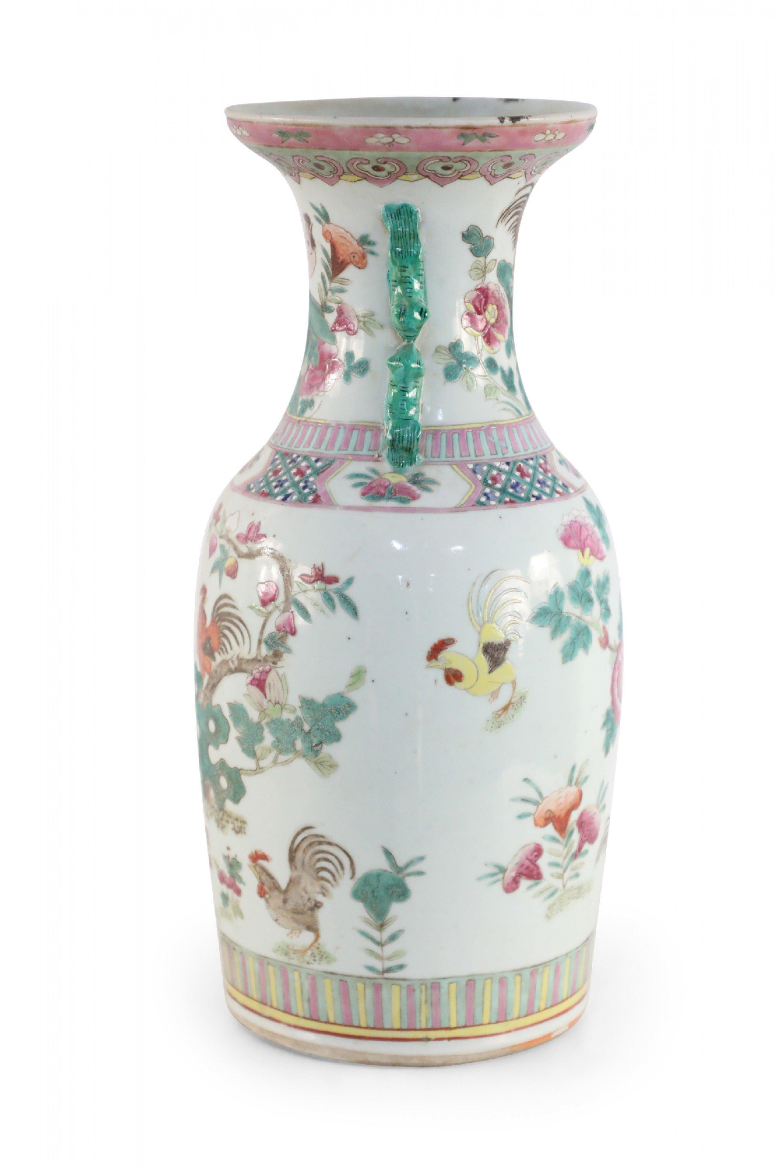 Antique Chinese (early 20th century) white porcelain urn incised and painted with decorations of roosters amid blooming floral branches mixed with geometric patterned bands at the bottom, middle and top accented with two green, scrolled lion handles