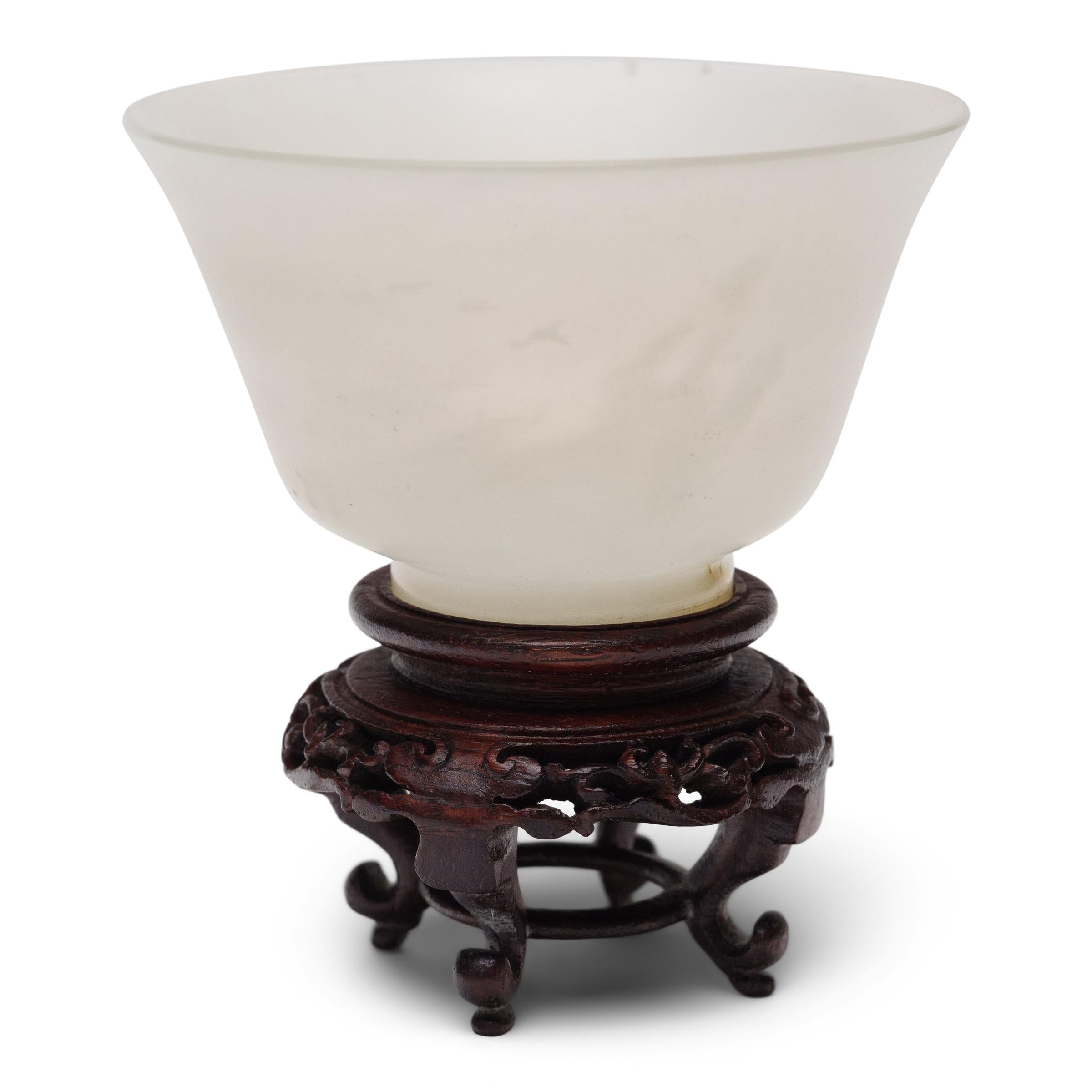 Minimal and refined, this elegant Chinese cup has a simple silhouette sculpted from a single piece of luminous white jade, carefully selected for its clarity and pale color. The delicate form is shaped with a flared lip, short footed base, and thin