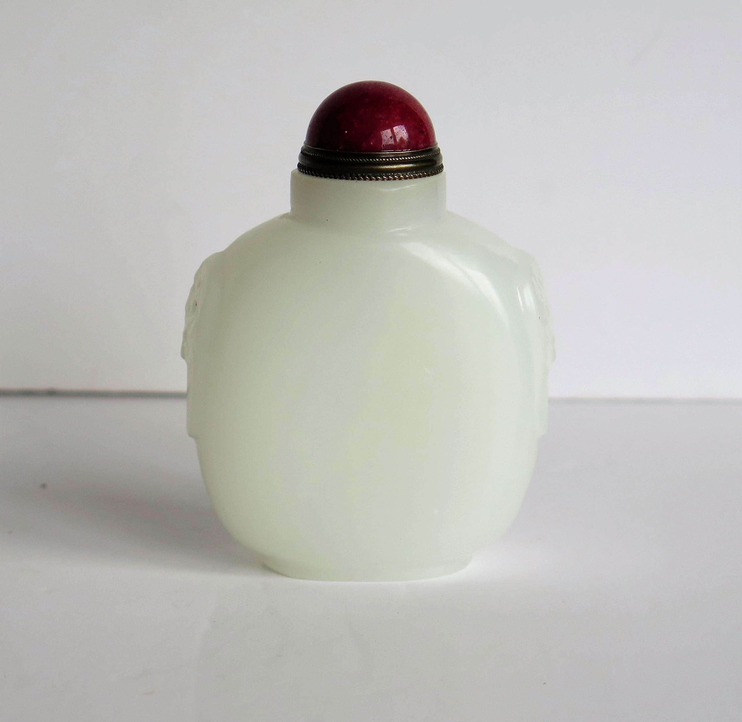 This is a beautiful Chinese, White Jade Snuff Bottle with a red stone top and spoon, dating to the mid 20th Century.

The bottle is hand carved and polished from white, 