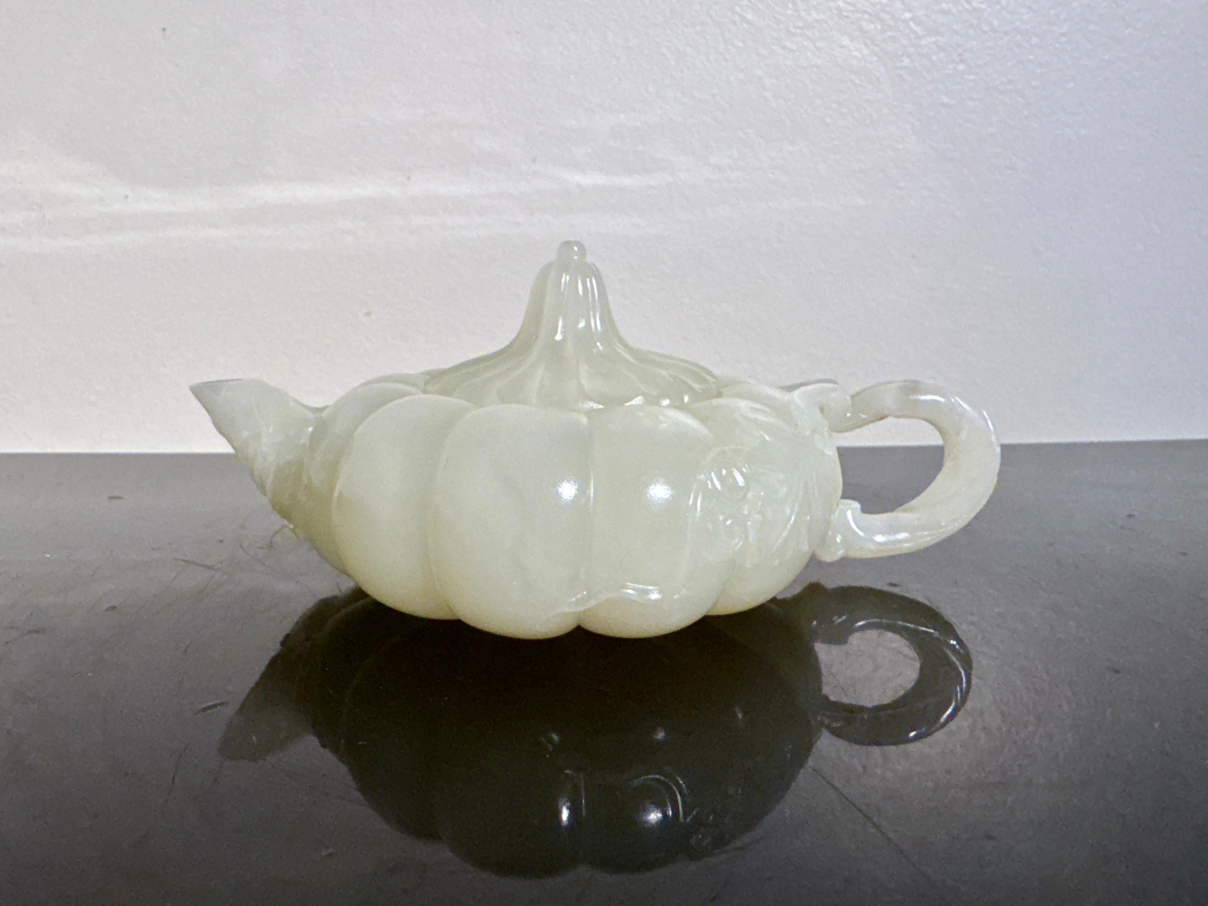 Théière en forme de melon en jade blanc ou en néphrite céladon très pâle, d'une extrême finesse, dynastie Qing tardive, vers 1900 ou avant, Chine.

L'élégante théière sculptée en forme de melon ou de citrouille trapue. Le corps globulaire comprimé