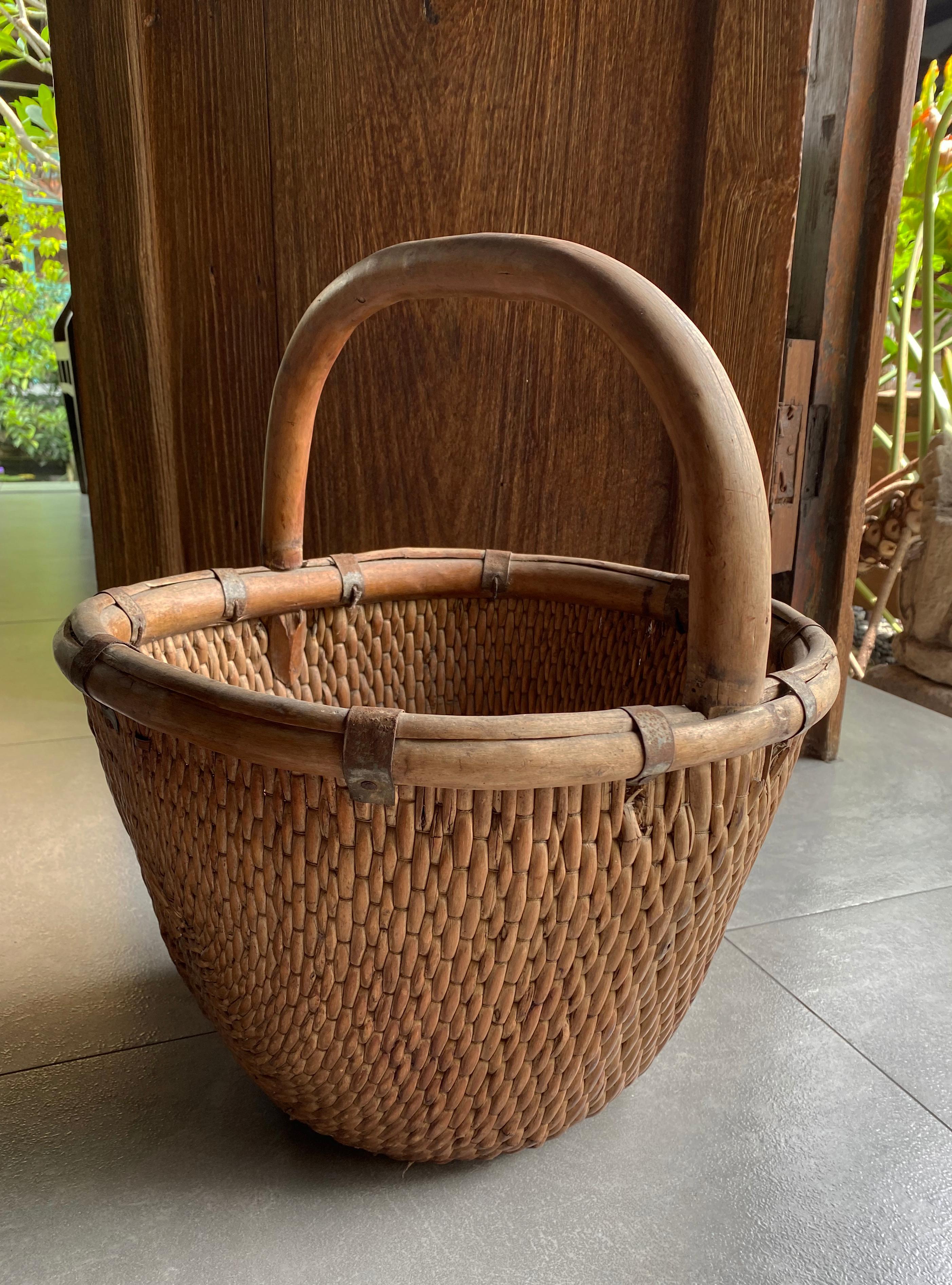 Ce panier est fabriqué à partir d'un cadre en bois et de roseaux de saule tressés provenant de la province chinoise de Shanxi. Utilisé pour transporter des grains, le cadre et la poignée lisse et texturée sont dotés de pinces en fer d'origine.