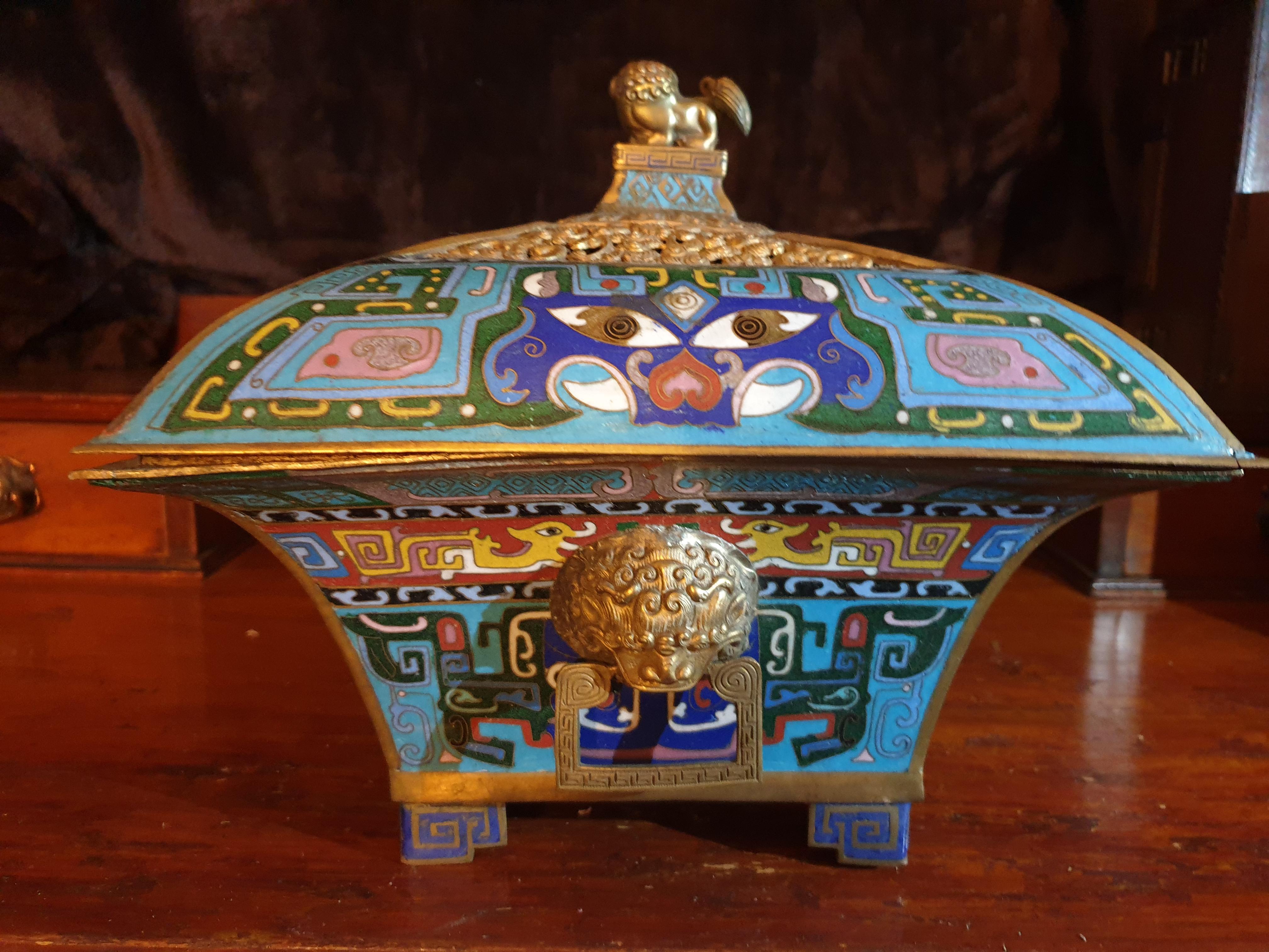An important Chinese square shaped Cloisonné Qing Dynasty incense burner, depicated with lion handles and gold gilt lion as on the lid. Reticulated gilt border scroll work with heavy attention to detail on the Cloisonné work with other mythical