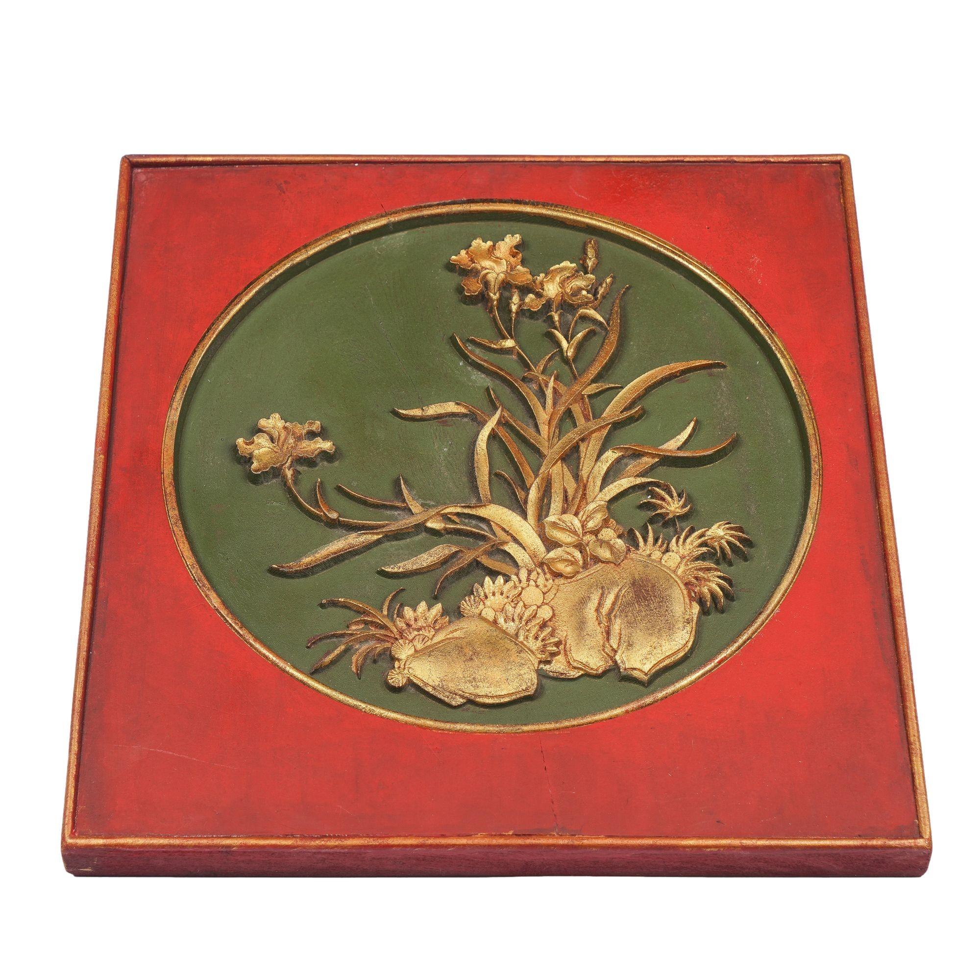 Square wood panel painted in red lacquer with a circular inset featuring shallow carved gilt cartouche on a green painted ground.
China, Qing Dynasty, 19th century.