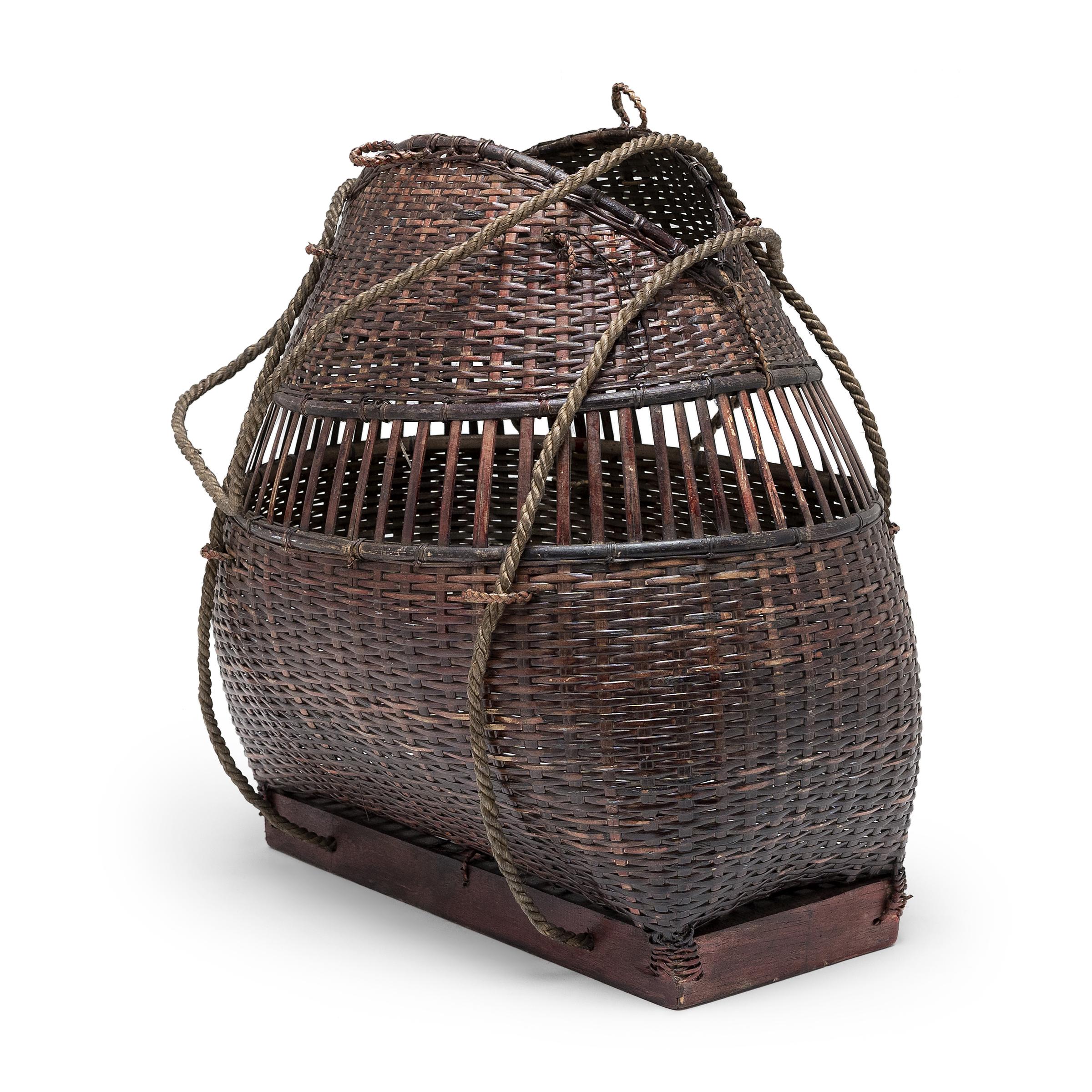 This smoky brown carrying basket originates from southeast Asia and is expertly crafted of thin strips of smoked bamboo. Carefully hand-woven in a plain weave with a band of exposed warp, the basket wonderfully showcases the artisan's mastery of