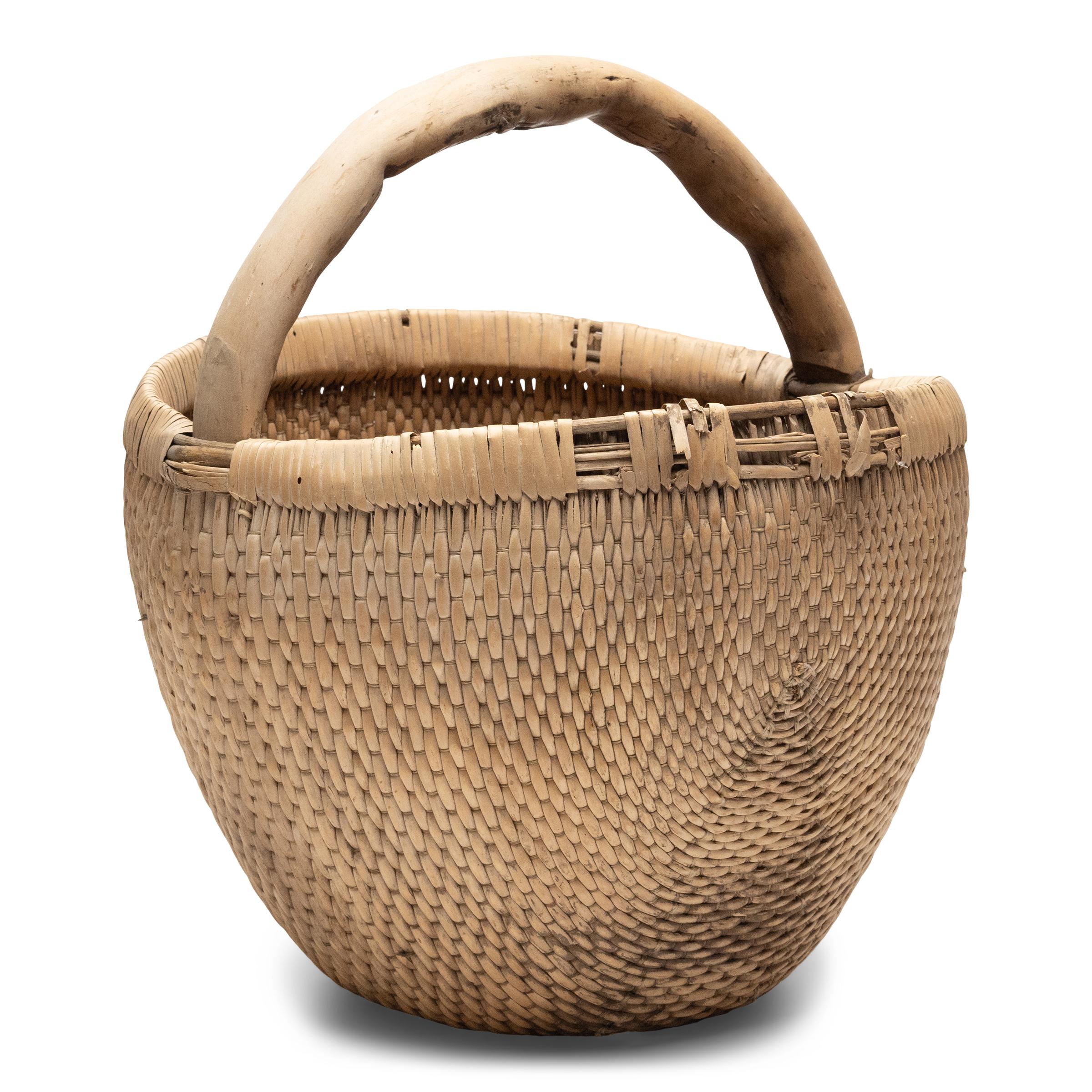 It is easy to imagine someone, long ago, gathering a harvest from their garden or strolling to the market with this beautiful basket tucked under their arm. Hand-woven of young willow branches and twine, the basket has deep, rounded body that tapers