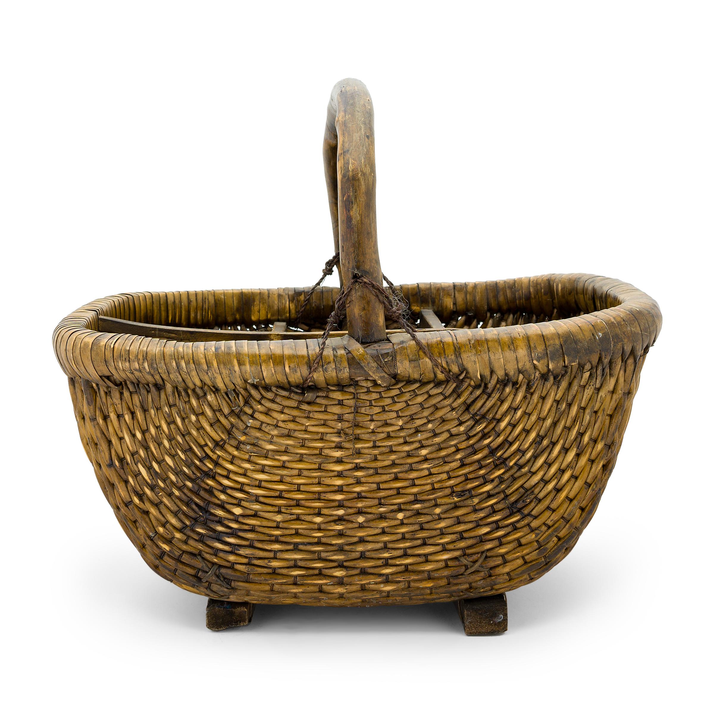 It is easy to imagine someone, long ago, walking to market on a summer's day with this beautiful woven basket tucked under their arm. Hand-woven of willow and twine, the basket has a rectangular form woven around a wooden rim and held by an arched
