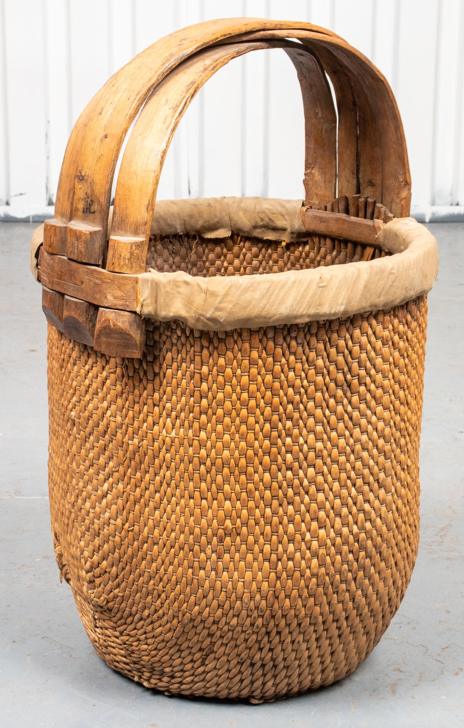 Chinese woven straw basket with triple slat curved handle. Measures: 25” height x 15.5” diameter.