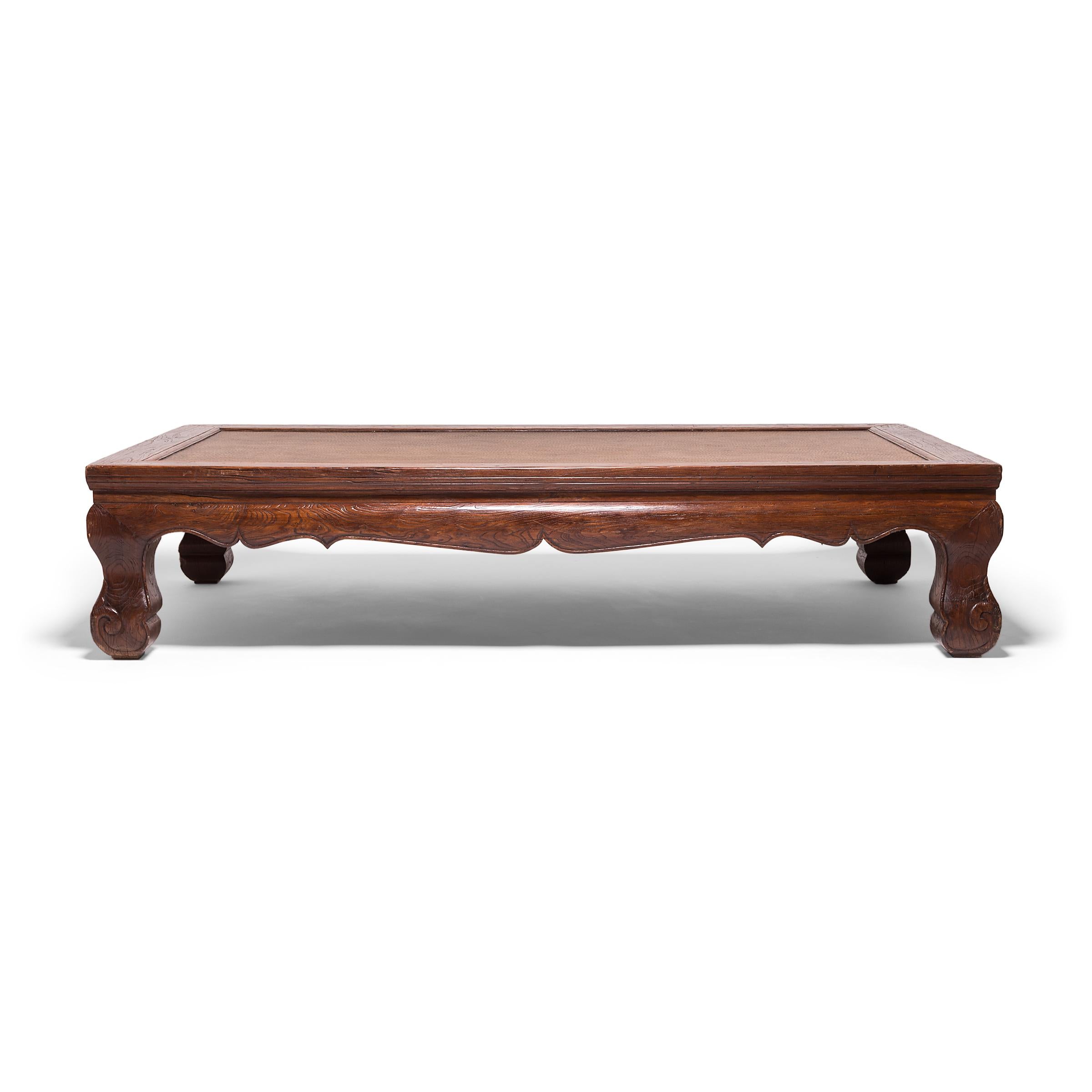 Questo monumentale letto da giorno in legno di olmo del XIX secolo, proveniente dalla provincia cinese dello Shanxi, presenta un grembiule che si incurva verso l'esterno con bordi cuspidati e un piano in rattan strettamente intrecciato. Le gambe