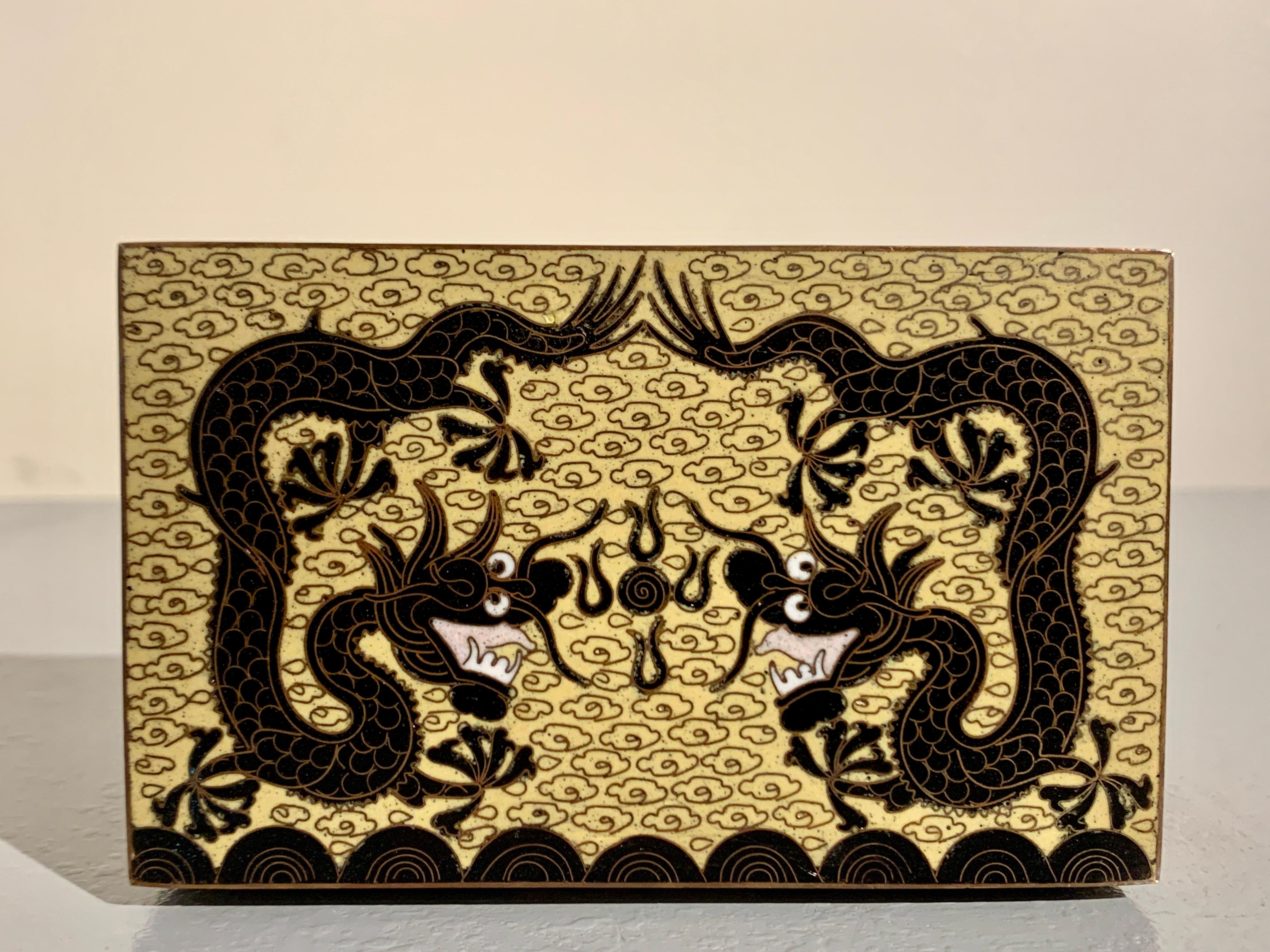 Charmante kleine chinesische Cloisonné-Schatulle mit Drachen, Republikzeit, um 1920, China.

Das kleine Kästchen steht auf vier Füßen und ist mit sich tummelnden Drachen aus schwarzem Cloisonné-Email auf gelbem Cloisonné-Grund gestaltet. Das Innere