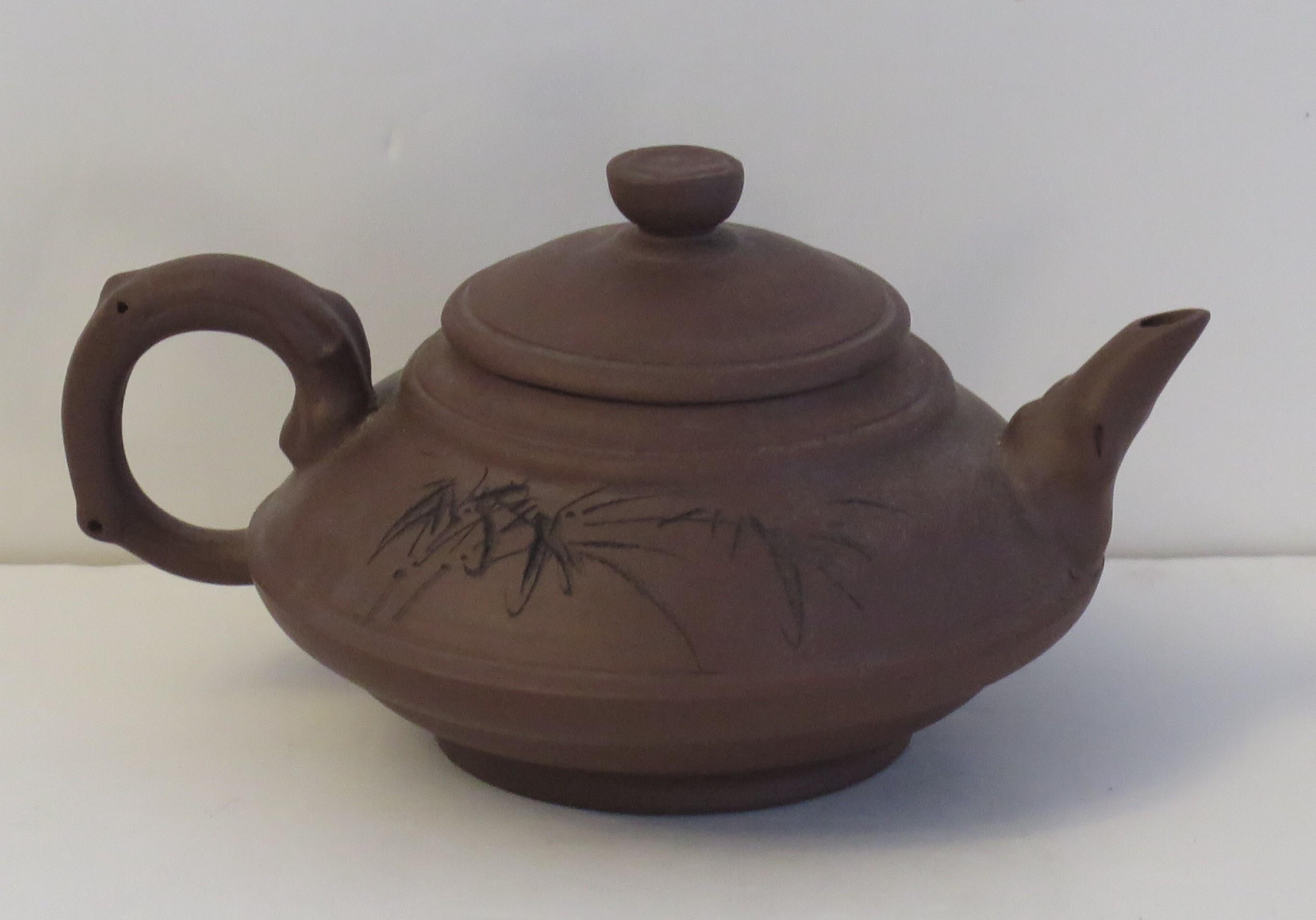 This is a Chinese handcrafted Red Clay Yixing teapot and cover, which we date to the 20th century, circa 1950.

The Teapot and lid are handcrafted in an interesting shape and made of Red Clay stoneware. The teapot is inscribed on the upper body with