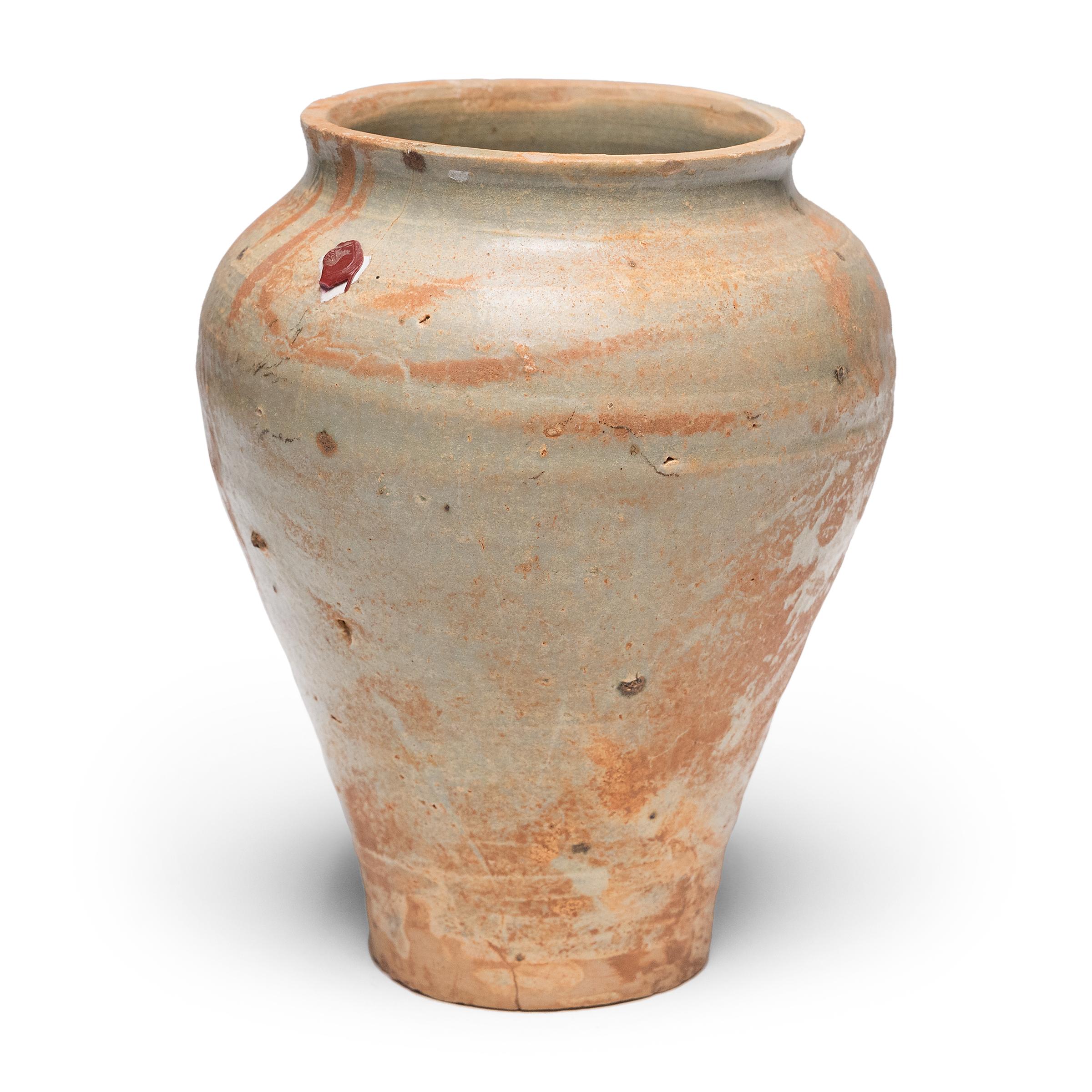 Avec la simplicité de sa forme et sa glaçure délicate, cette jarre de la dynastie Yuan (1279-1368) destinée à contenir de l'alcool de riz ou des spiritueux témoigne du raffinement tranquille des céramiques provinciales chinoises. La forme en terre