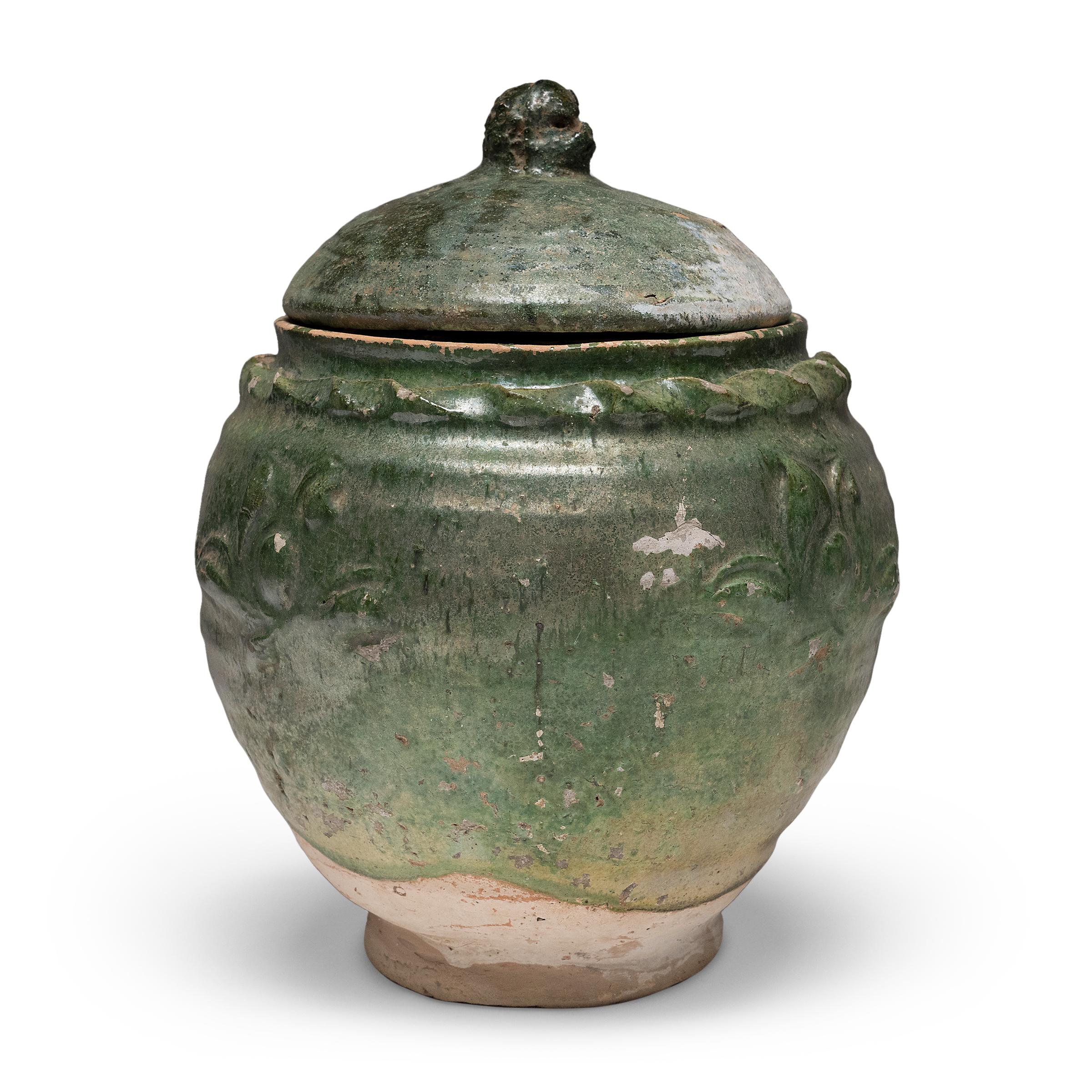 Belle dans son imperfection, cette jarre à couvercle émaillé vert de la province du Yunnan est un récipient à offrandes, ou jarre à esprits, qui contenait à l'origine des offrandes rituelles telles que des pièces de monnaie, des coquillages, des