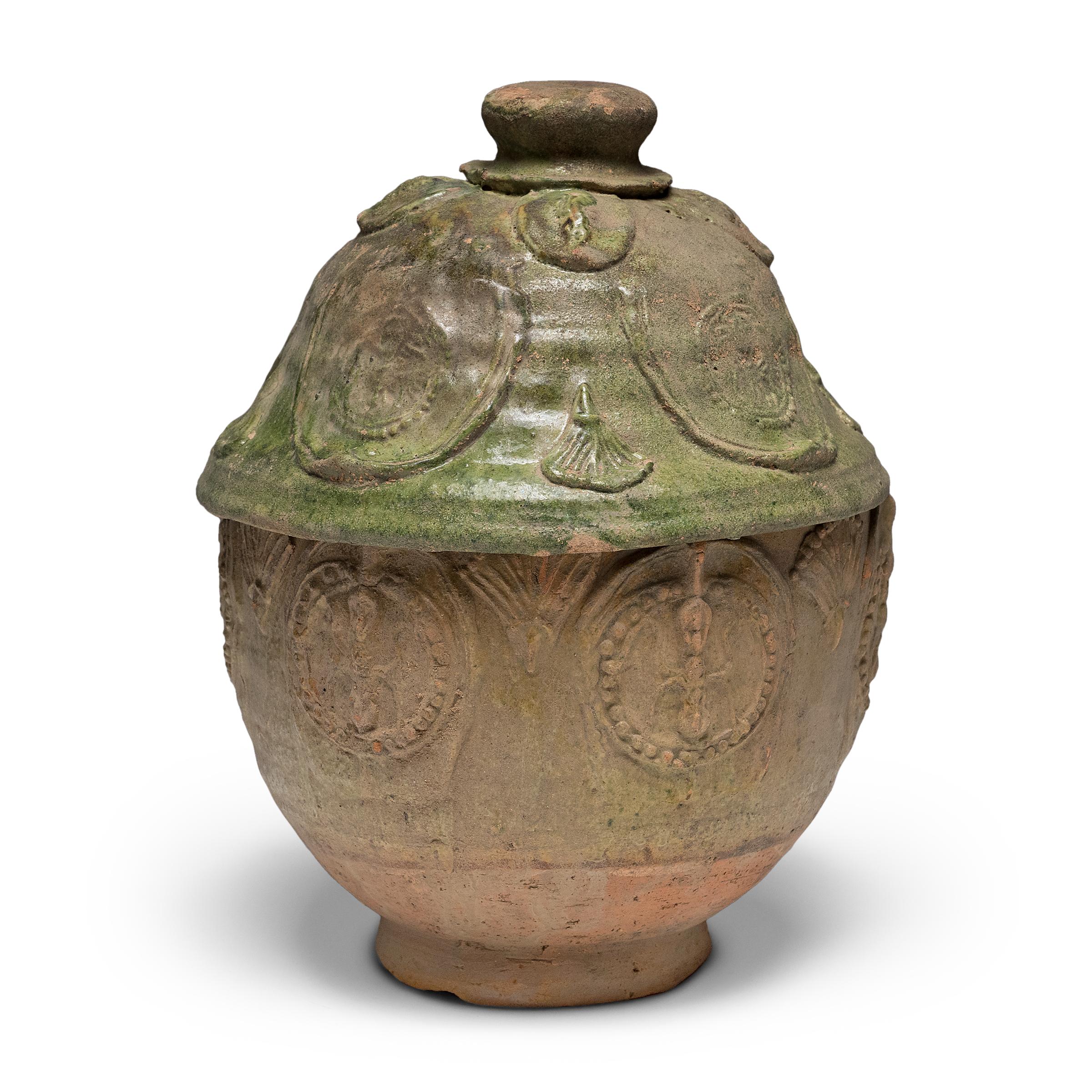 Belle dans son imperfection, cette jarre à couvercle émaillé vert de la province du Yunnan est un récipient à offrandes, ou jarre à esprits, qui contenait à l'origine des offrandes rituelles telles que des pièces de monnaie, des coquillages, des