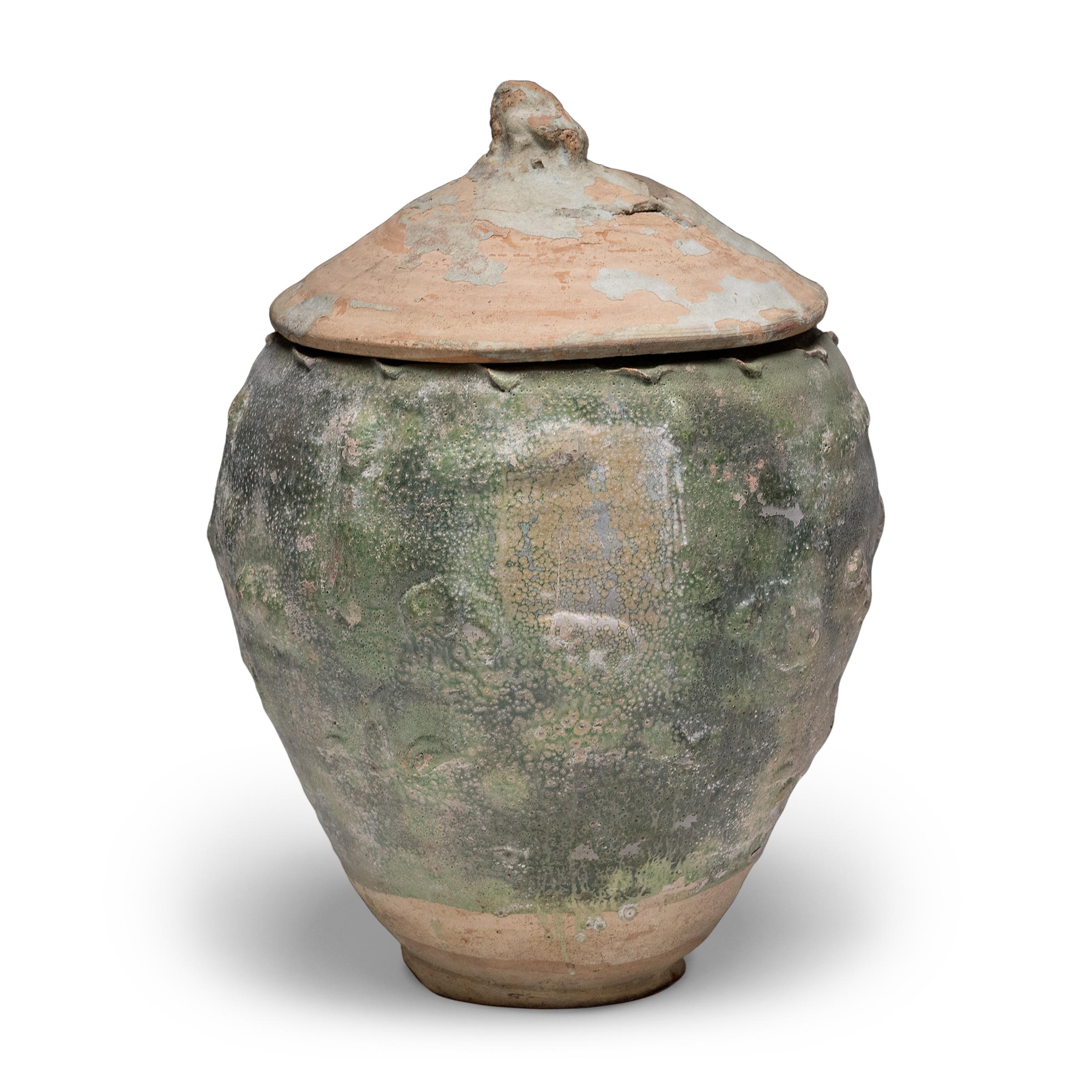 Belle dans son imperfection, cette jarre à couvercle émaillé vert de la province du Yunnan est un récipient à offrandes, ou jarre à esprits, qui contenait à l'origine des offrandes rituelles telles que des pièces de monnaie, des coquillages, des