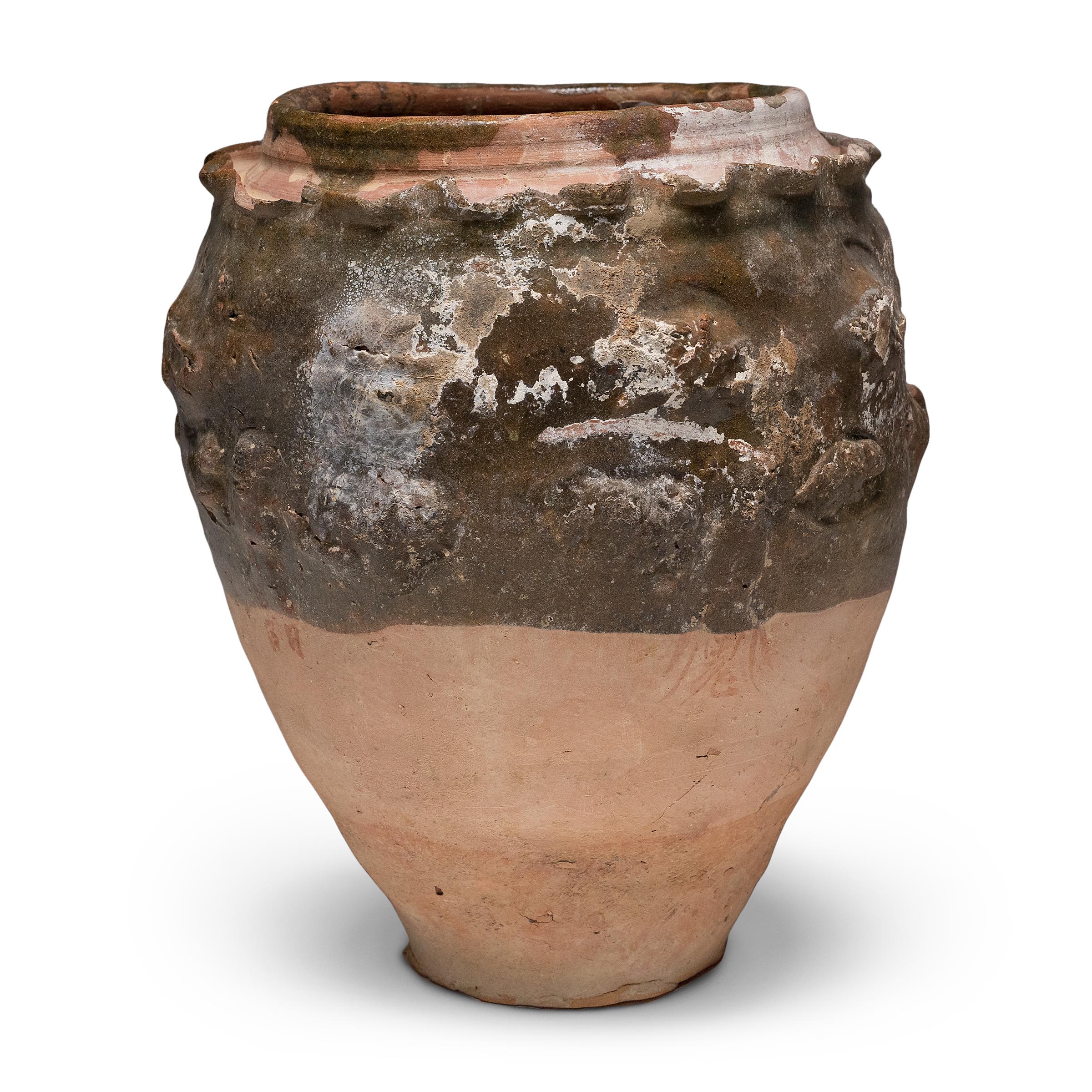 Beautiful in its imperfection, this green glazed jar from Yunnan province is an offering vessel, or spirit jar, originally filled with ritual offerings such as coins, shells, flowers and grains. Attributed to the Yuan dynasty (1271-1368) or earlier,
