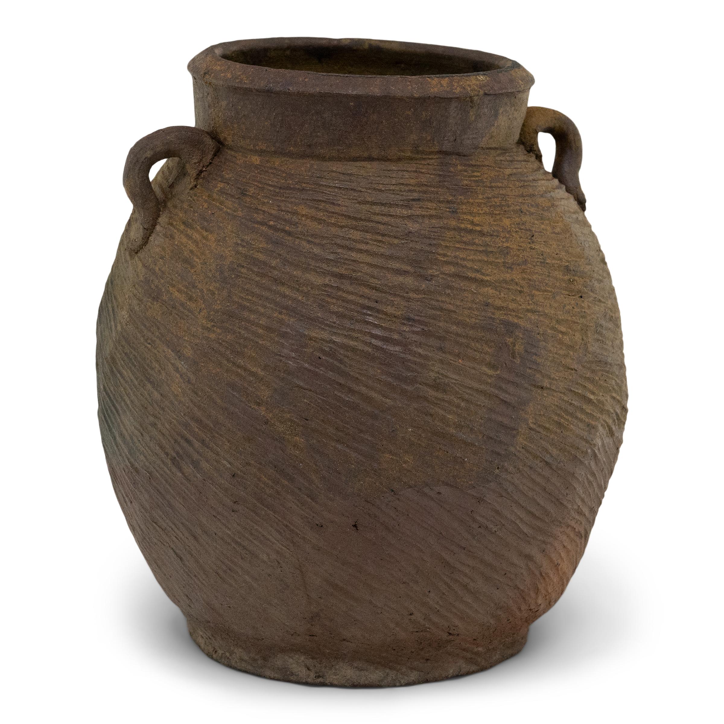 Charged with the humble task of storing dry goods, this small terracotta pot was hand-shaped in the 19th century with balanced proportions and a beautifully irregular brown slip finish. The lobed pot features a round form with a narrow base and a