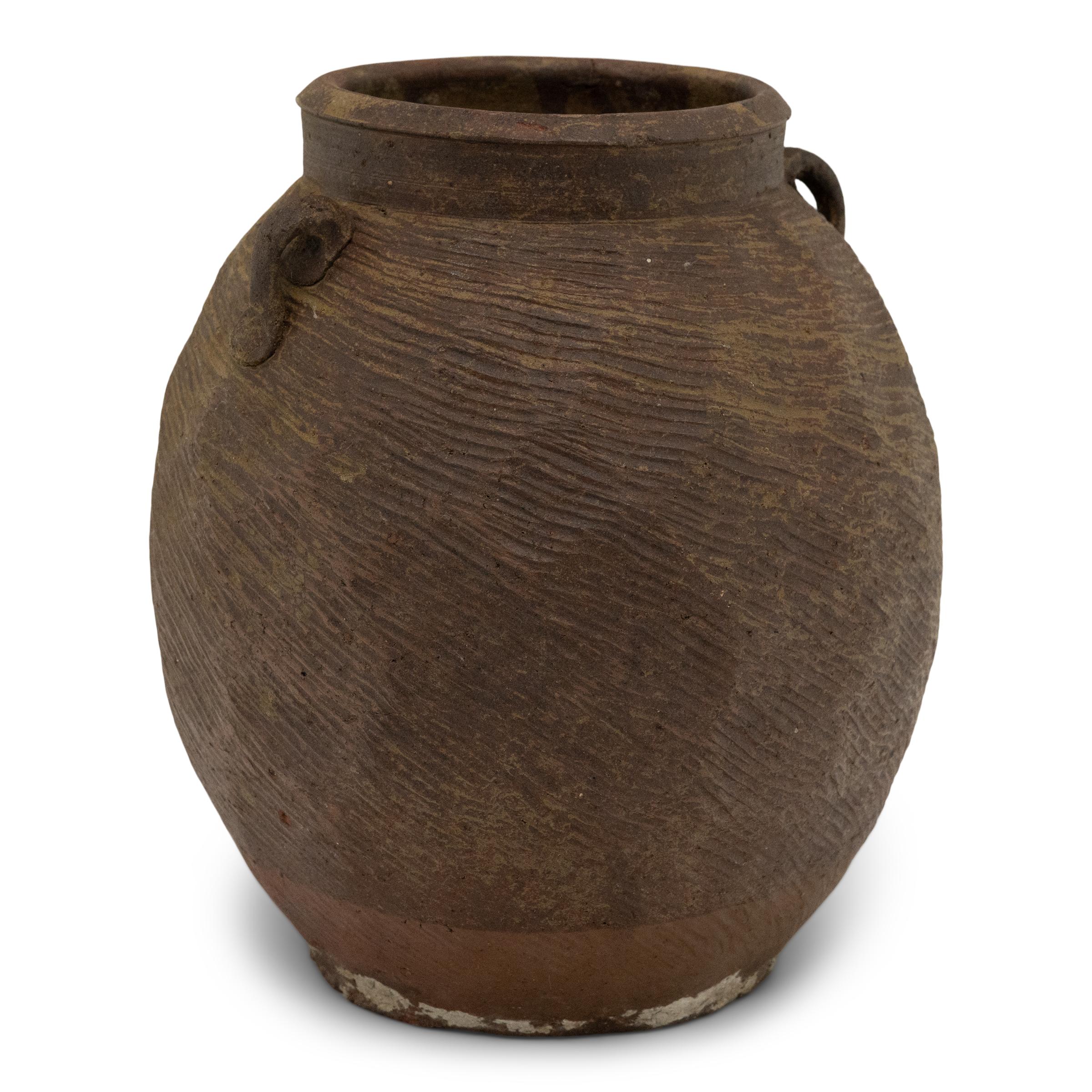Charged with the humble task of storing dry goods, this small terracotta pot was hand-shaped in the 19th century with balanced proportions and a beautifully irregular brown-green slip finish. The lobed pot features a round form with a narrow base