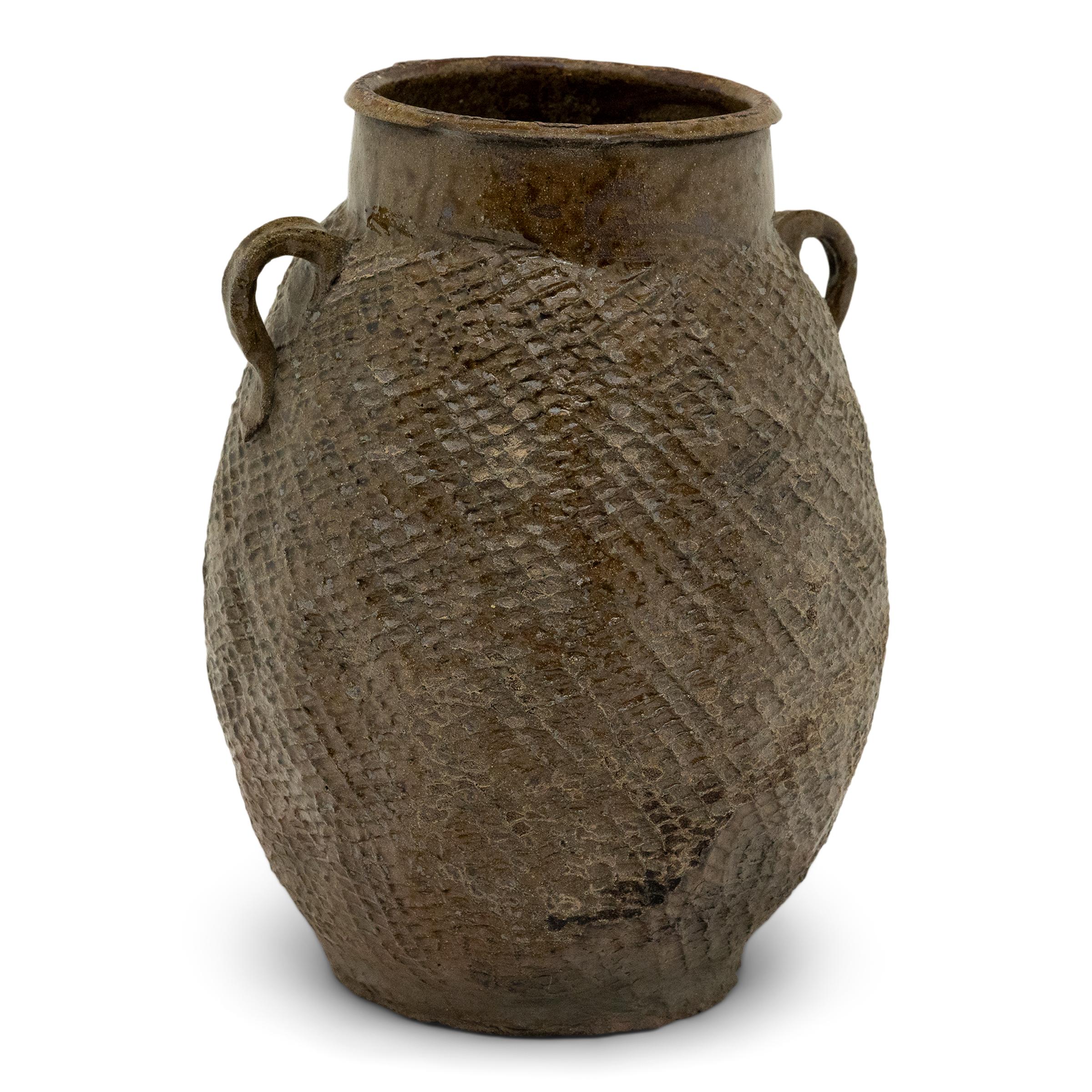 Cloaked in a beautifully irregular brown-green slip finish, this 19th-century earthenware pot was charged with the humble task of storing dry goods in a Qing dynasty kitchen. The lobed pot has a round form with a narrow base and a tall neck flanked