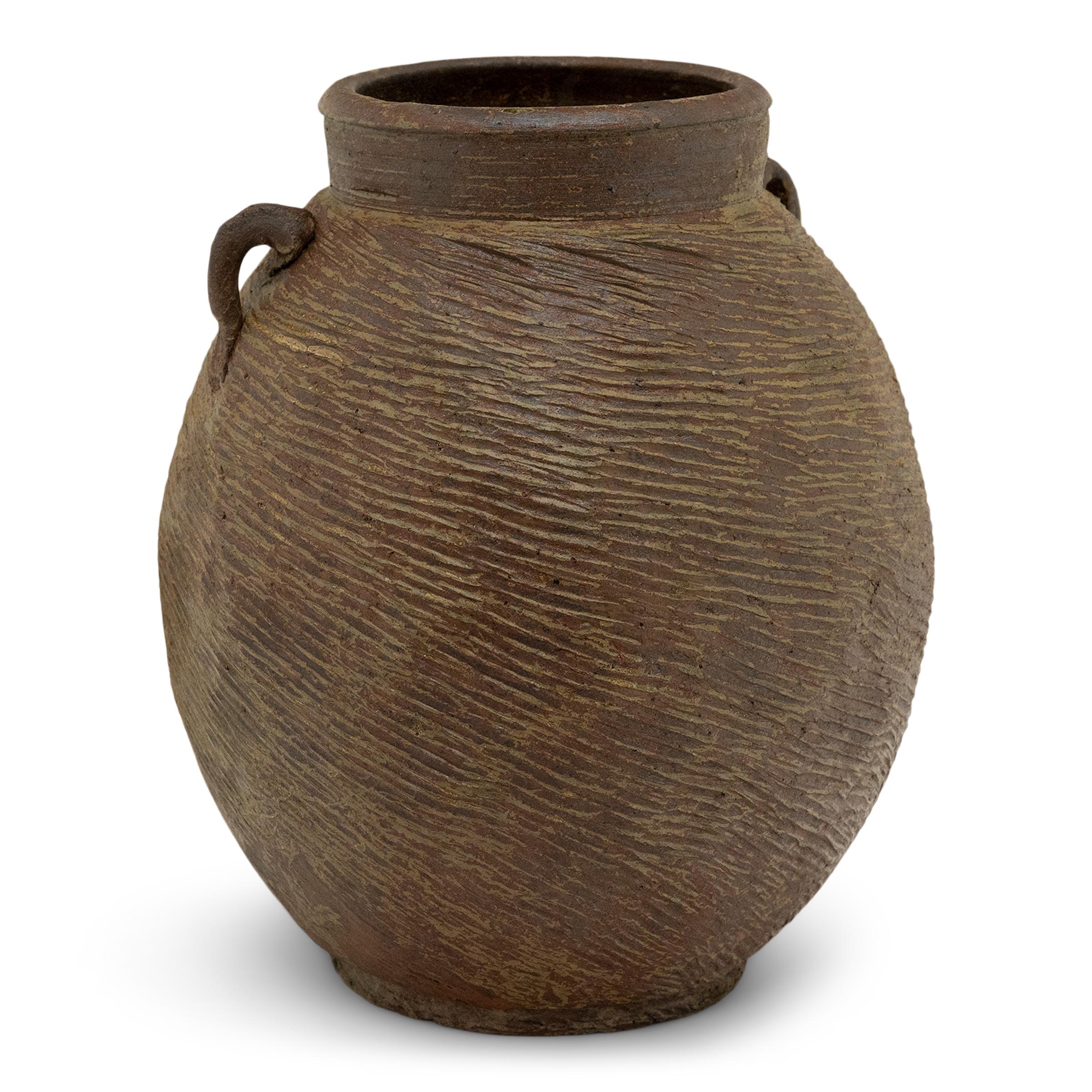Cloaked in a beautifully irregular brown-green slip finish, this 19th-century earthenware pot was charged with the humble task of storing dry goods in a Qing dynasty kitchen. The lobed pot has a round form with a narrow base and a tall neck flanked