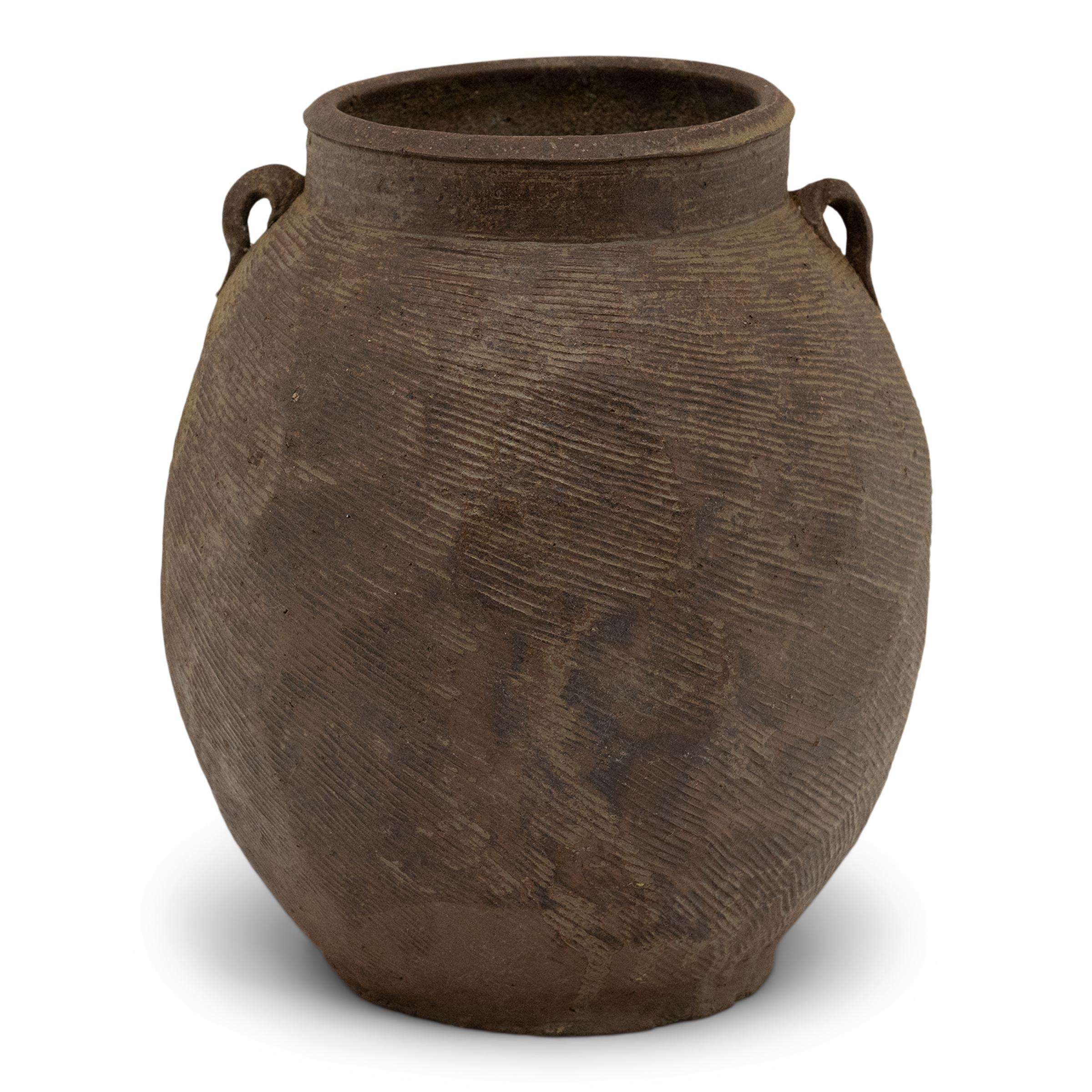 Cloaked in a beautifully irregular brown slip finish, this 19th-century earthenware pot was charged with the humble task of storing dry goods in a Qing dynasty kitchen. The lobed pot has a round form with a narrow base and a tall neck flanked by two