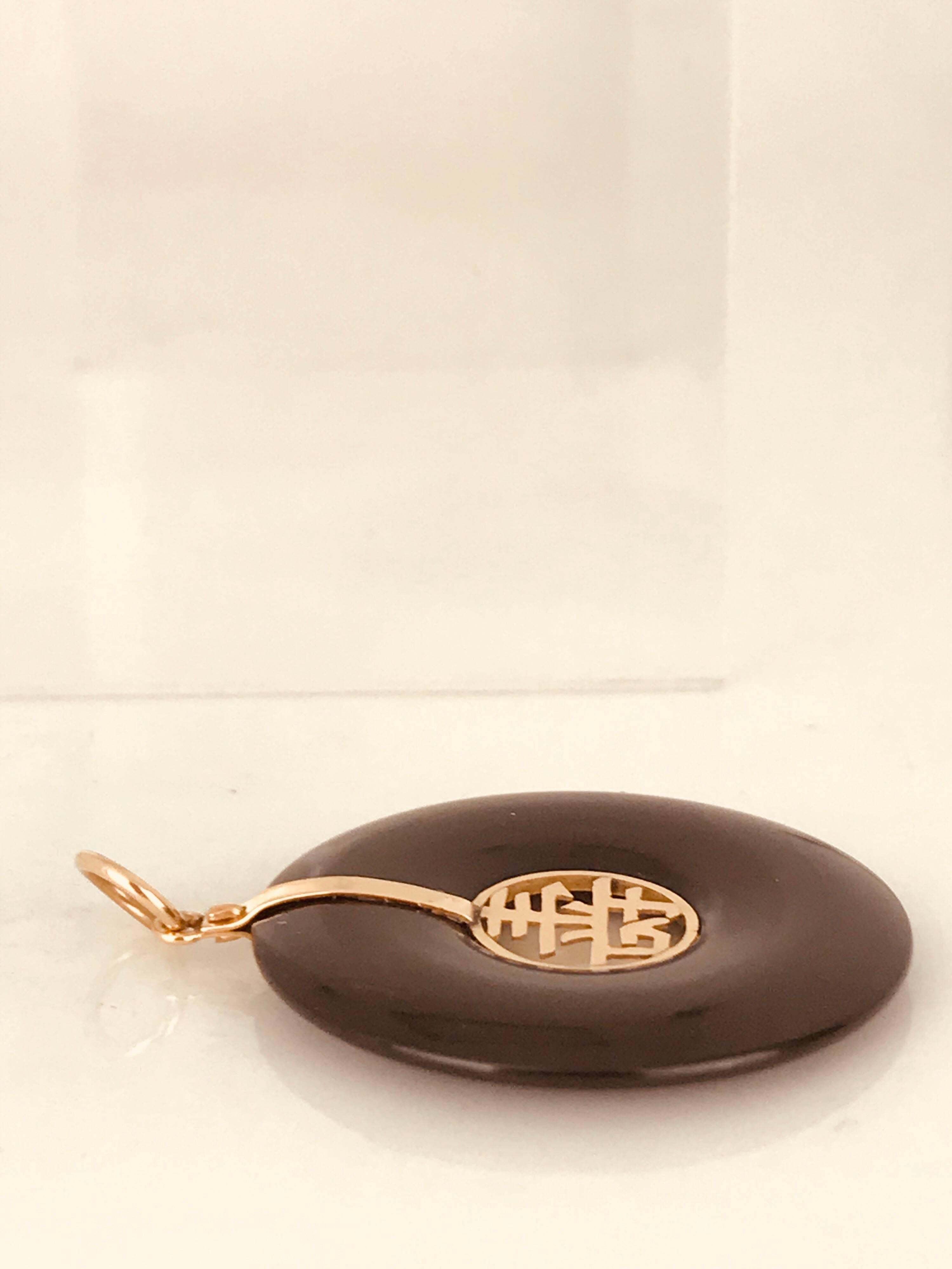 14 karat yellow gold, Chinese good-luck pendant with hallmark HK and 14 Kt. 
The Black onyx is concave measuring 1.24 inches in diameter. The gold insert measures .42 inches.
Circa 1965, this retro pendant has a beautiful luster. 

GIA Gemologist,