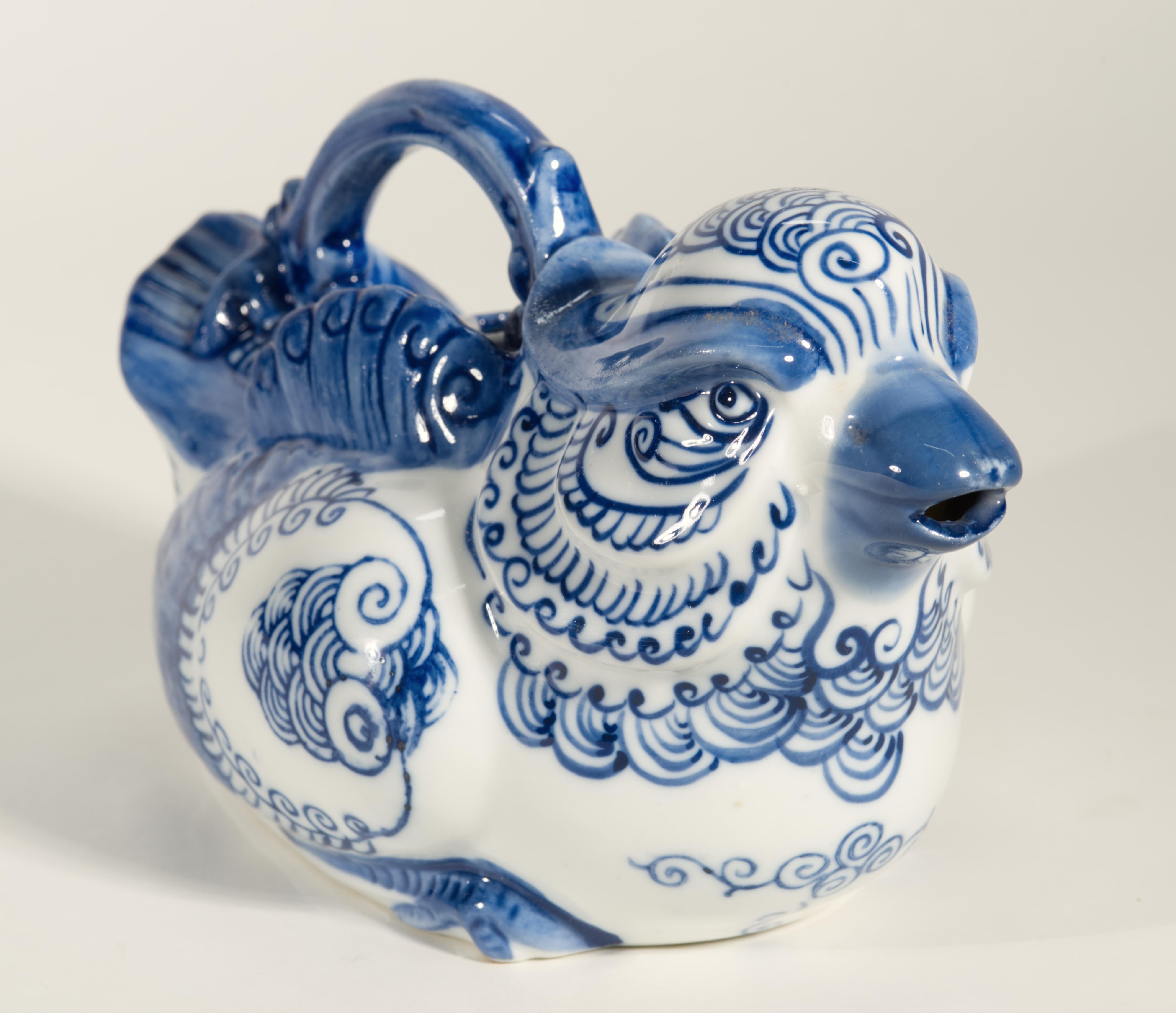 La piccola teiera in ceramica o porcellana vintage è scolpita a forma di uccello o fenice, con testa grande, ali lunghe, coda arrotondata e manico decorato sul retro. La teiera presenta il tradizionale decoro Chinoiserie blu su bianco con motivi