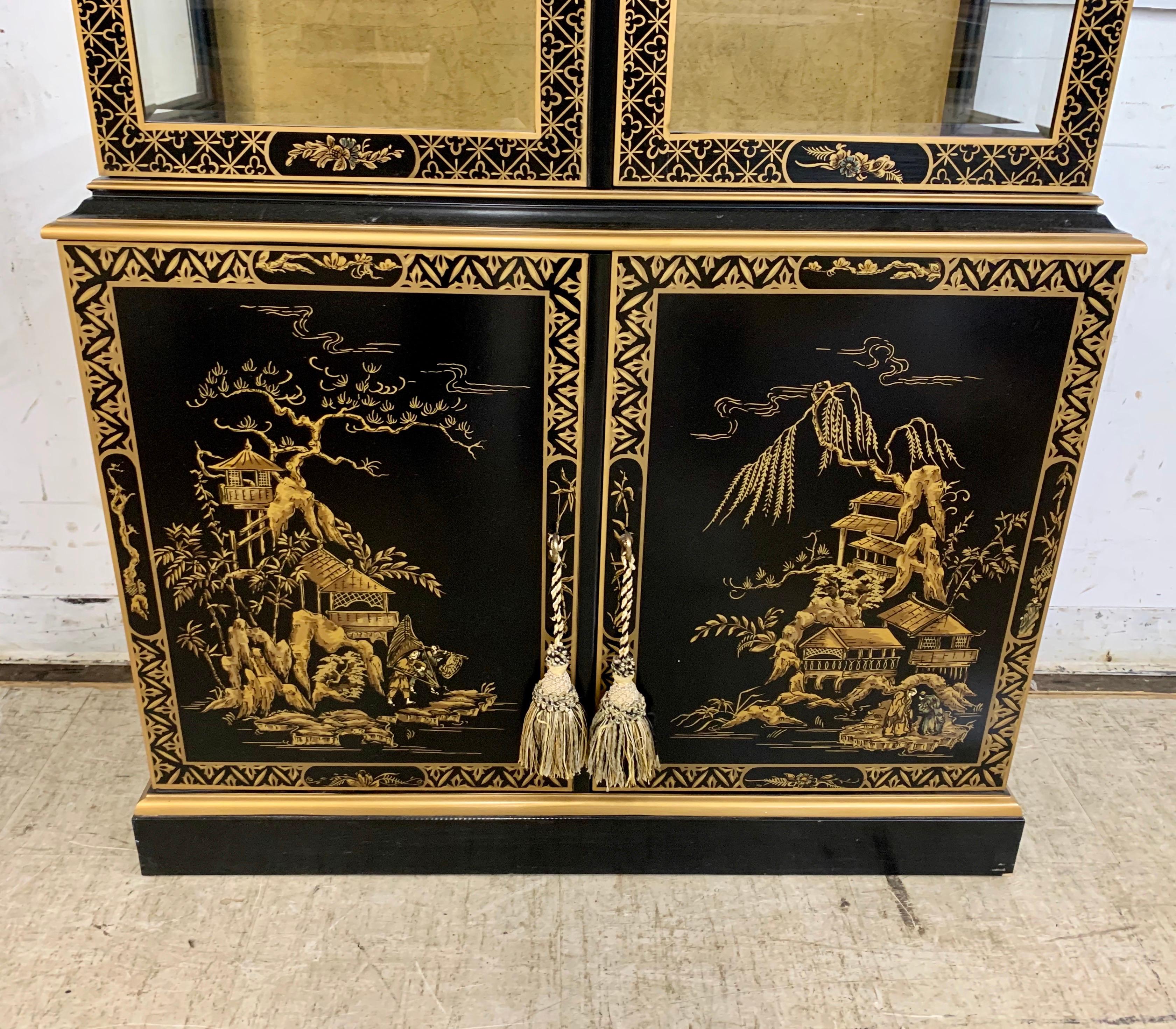 Black lacquered china cabinet by Drexel in Chinese chinoiserie style features hand painted gold scenery on three sides. It has lighted interior with glass shelves. Very good condition with only very minor imperfections consistent with age.