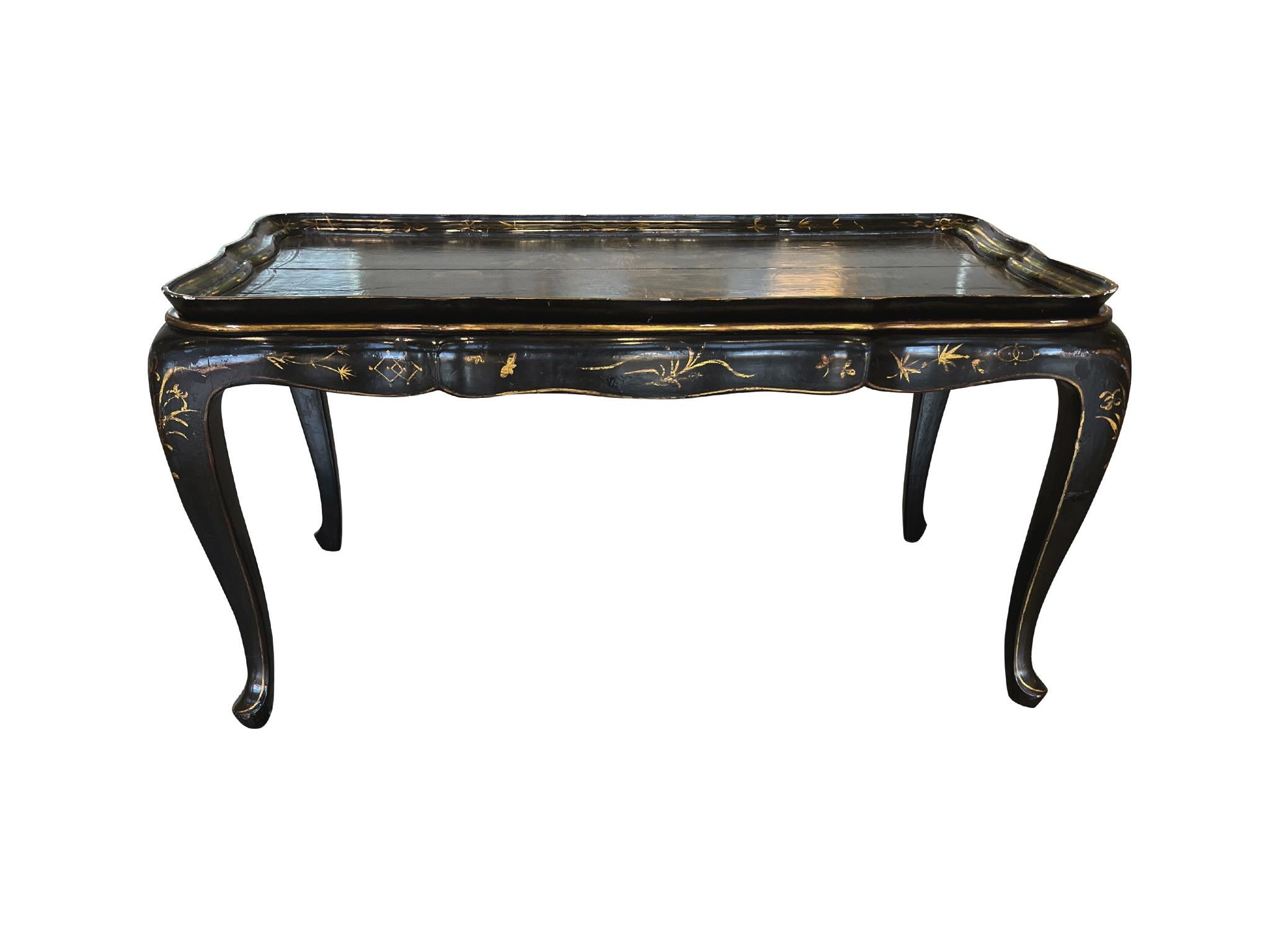 Made in the 1930s, this wood chinoiserie tray table consists of a detachable tray top and base, both in a rich black lacquer and parcel gilt decor. A hand-painted gilt landscape adorns the tray surface. We love the scalloped rim of the tray, which