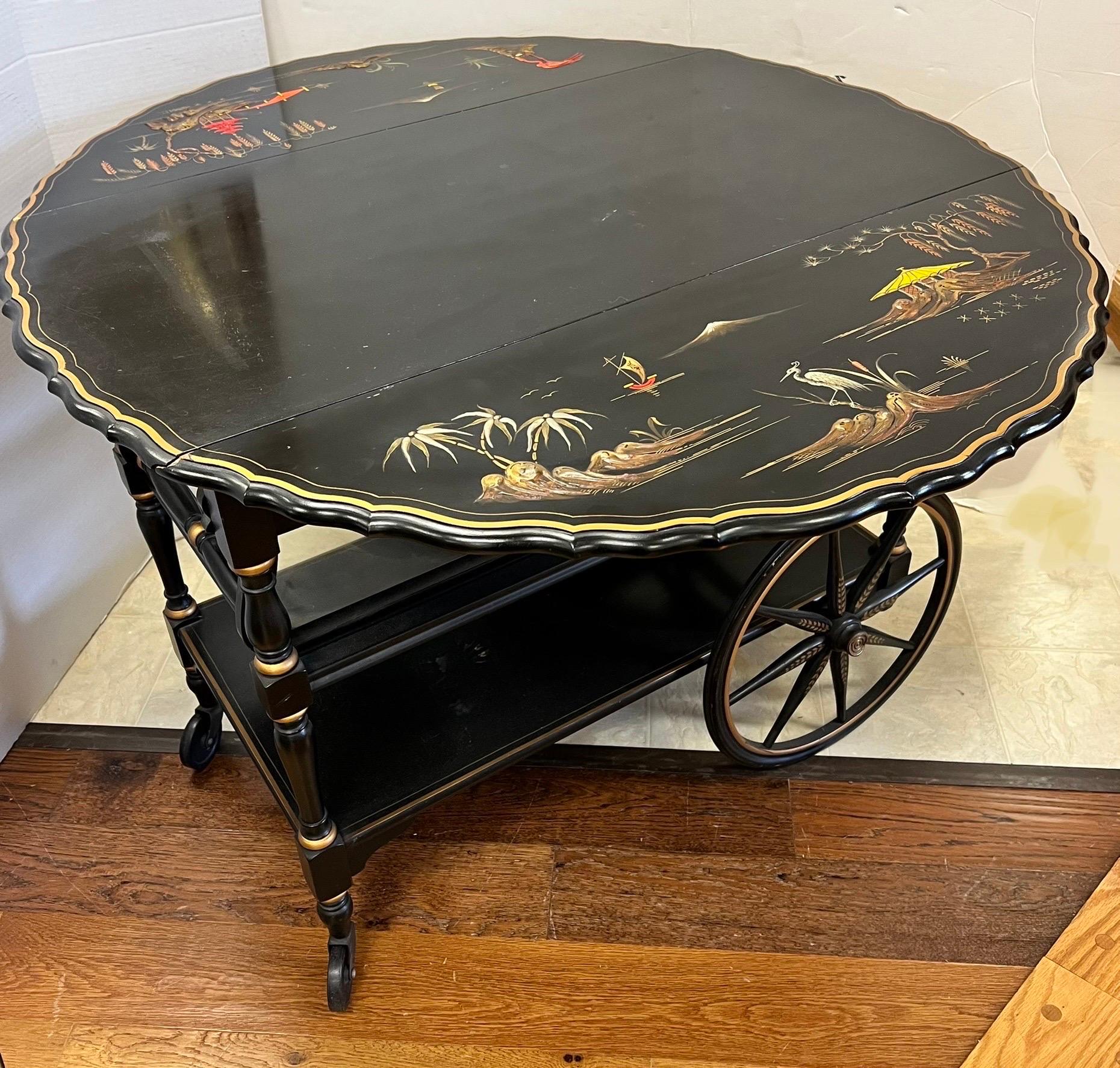 Beautiful vintage black lacquered bar cart expands to a round table when sides are raised. Elegantly hand painted with a classic Chinese landscape motif over the lustrous black lacquer surface. The large spoke wheels paired with small castors in the