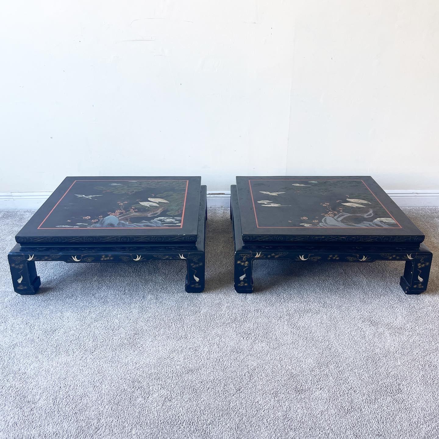 Amazing pair of black lacquered coffee tables made in Hong Kong. Stunning depictions of birds and nature hand painted onto each table.