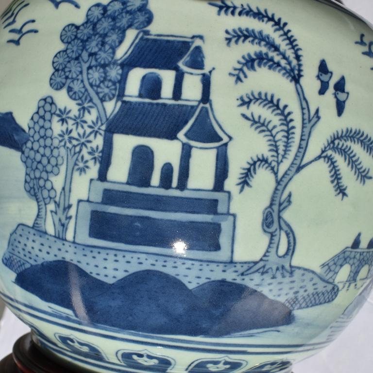 Tall Chinese ceramic or porcelain Canton lamp in blue and white. In a fantastic round gourd shape, and wood base this is a piece that will stand out in any space. Painted scenes in blue of pagodas, waterfalls, mountains and various flora and fauna.
