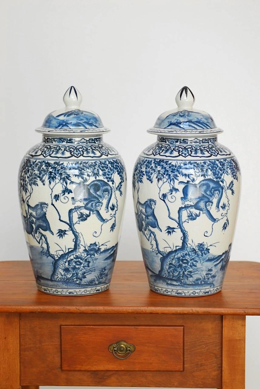 Stunning pair of chinoiserie painted blue and white ginger jars featuring scenes of monkeys at play. Each lidded urn has a continental style delft faience mark on the bottom with the initials C.H. Beautifully glazed with a craquelure finish.