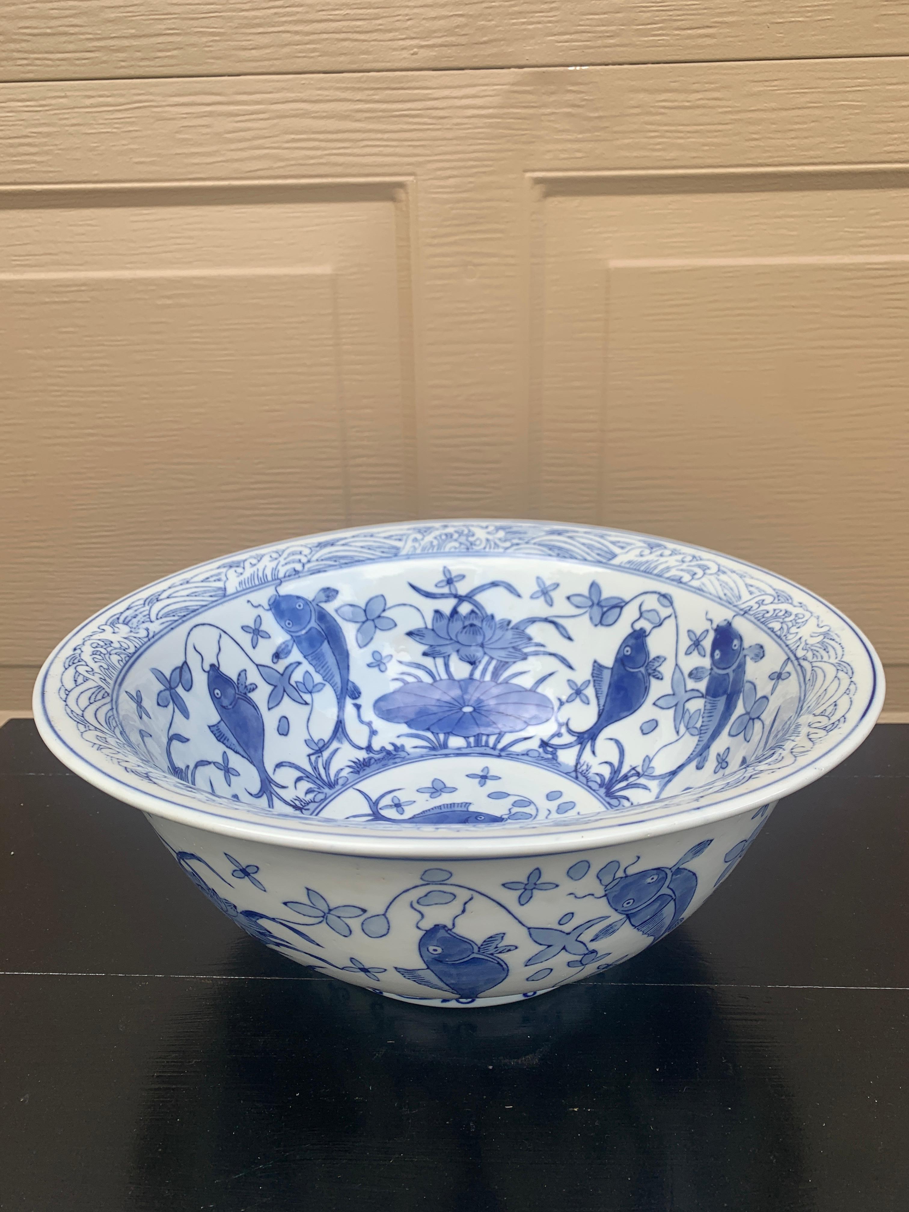 Magnifique cache-pot ou bol décoratif en porcelaine bleue et blanche de Chinoiserie, avec des motifs floraux asiatiques et des poissons.

Chine, Fin du 20e siècle

Mesures : 14,25 