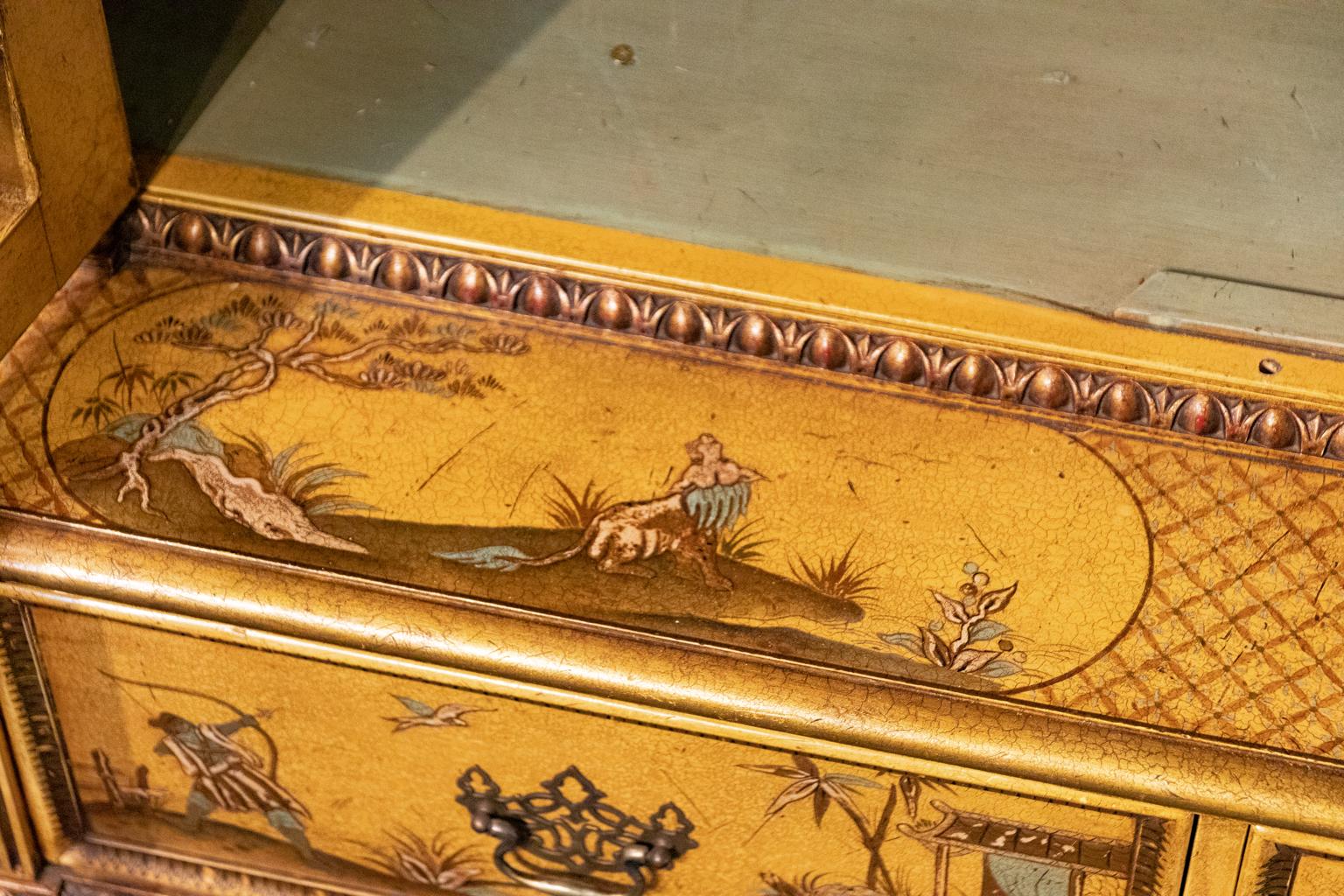 Circa 1890s Georgian Chinoiserie style decorated two door, glass front bookcase with two drawers and five shelves on lion's paw feet. The piece is also gilded and detailed throughout with Chinoiserie decorations such as foliage, flowers, and birds