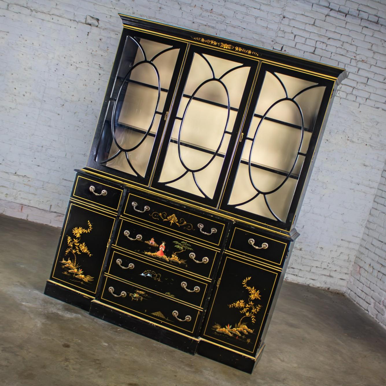 Gorgeous vintage Chinoiserie breakfront China hutch cabinet or drop front secretary bookcase composed of 2 pieces, each with black lacquered wood frames with an all-over intentional distressed finish & hand painted Asian details. The top hutch is
