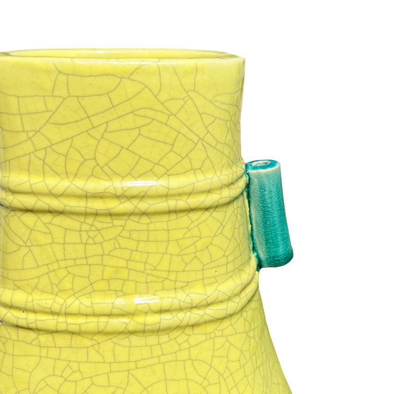 A tall chinoiserie yellow ceramic vase with bright green handles. This piece is from an excursion in Hong Kong. It features a thick ceramic clay exterior and is hand painted with a bright lemon yellow craquelure paint. The sides feature round ridges