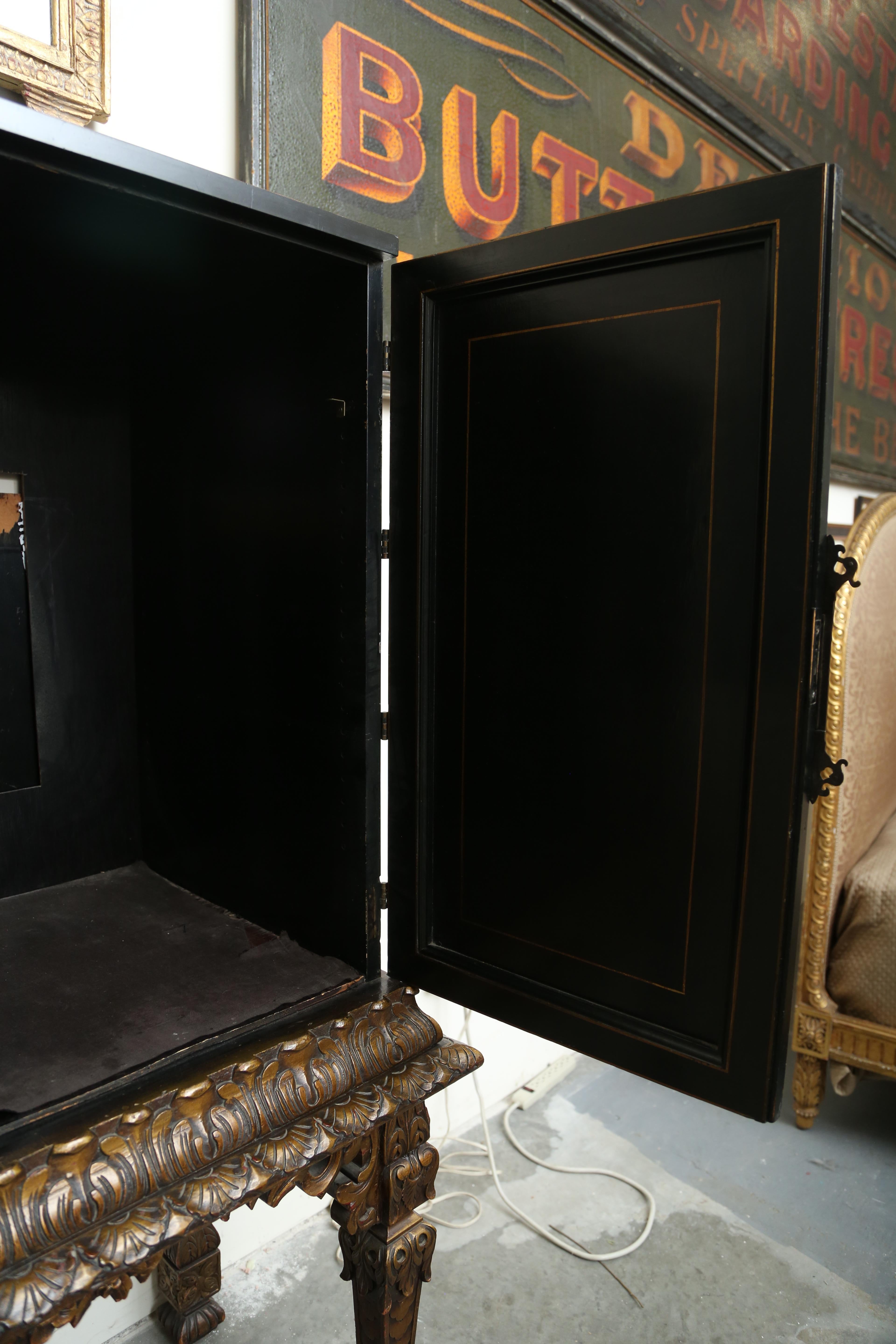 Chinoiserie two-door black lacquer cabinet with raised gilt and lacquer decorations. Engraved bass hardware and hinges with original key. The cabinet rests on a carved gilt stand. The interior could be fitted with a mirrored back and glass shelves