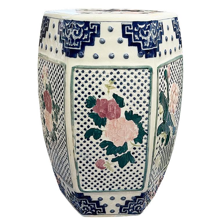 A petite ceramic chinoiserie garden stool with hand-painted cherry blossom flower motifs in pink and green. The top of the stool features a pierced medallion with soft pink and blue painted designs. This would be a great piece on a patio used as