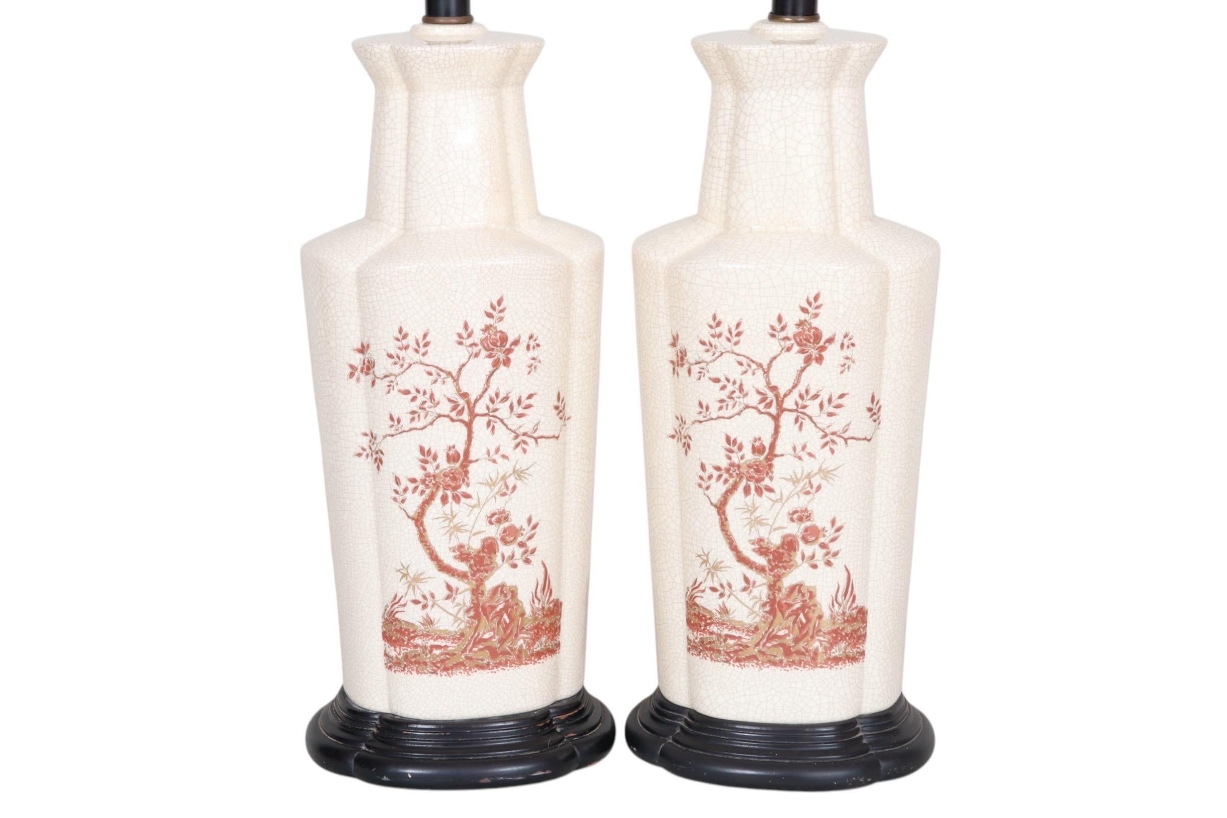 Paire de lampes de table en céramique de style chinois. Les vases en céramique peints à la main sont décorés de rosiers bordeaux et or, sur une base en craquelure crème. Les vases sont godronnés et les bases en bois sont étagées et laquées en noir.