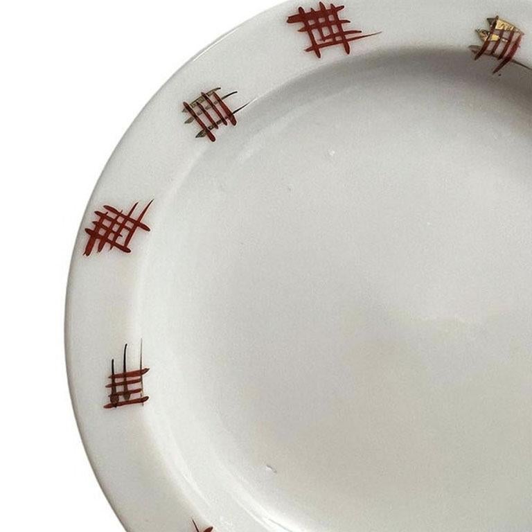 A petite round ceramic trinket dish in white, with red and gold characters. This small piece will be great for a nightstand or dressing table to hold small items such as change or trinkets. The entire piece is glazed in a bright white, and around