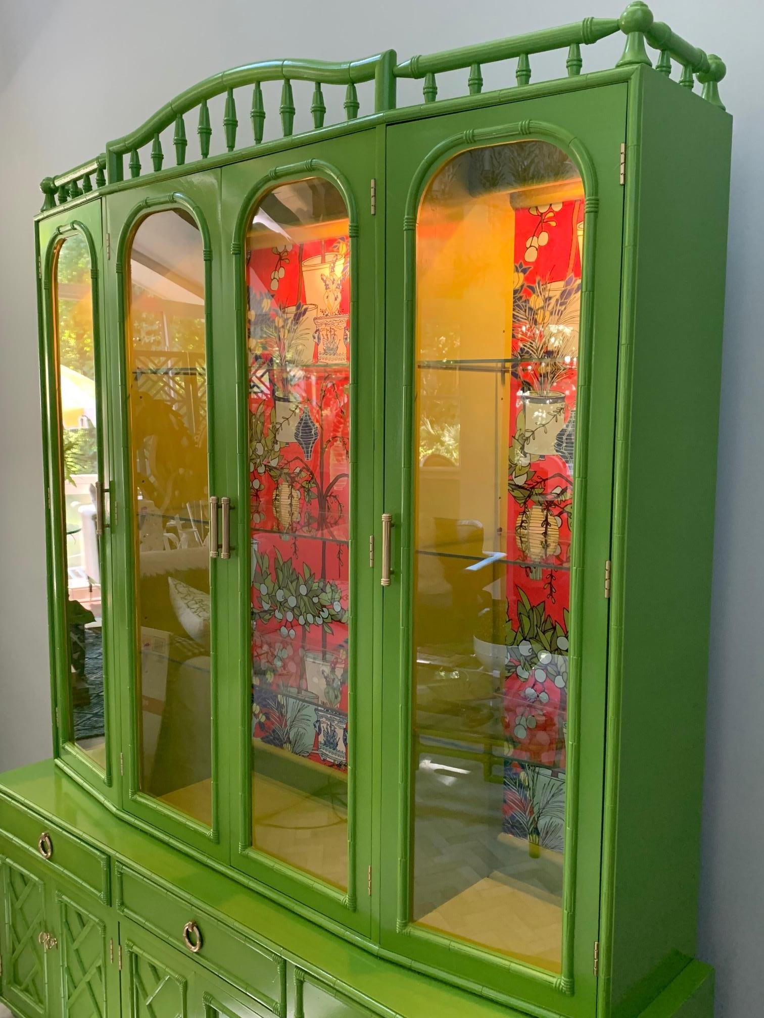 Freshly lacquered Asian chinoiserie style two-piece china cabinet makes a real statement with its stunning high gloss green finish and bold wallpaper detailing. Faux bamboo accents adorn doors and drawers. Excellent condition with only minor