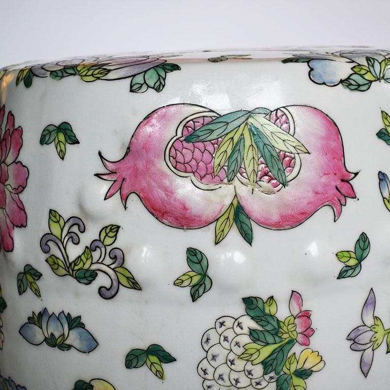 Famille Rose chinoiserie colorful garden seat in pink, yellow and green. 

Round in form, this ceramic piece is painted with figurative examples and flora and fauna in rich berry colors such as pink lotus leaves, peacocks in a deep emerald green and